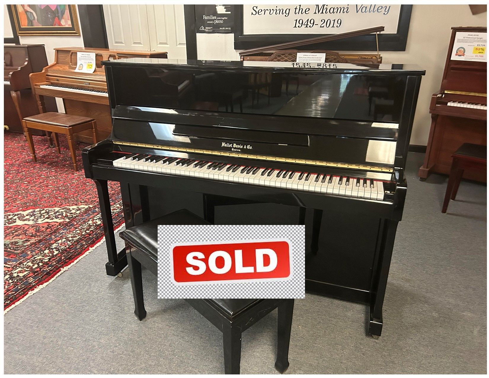 A black upright piano is sitting in a room with a bench.