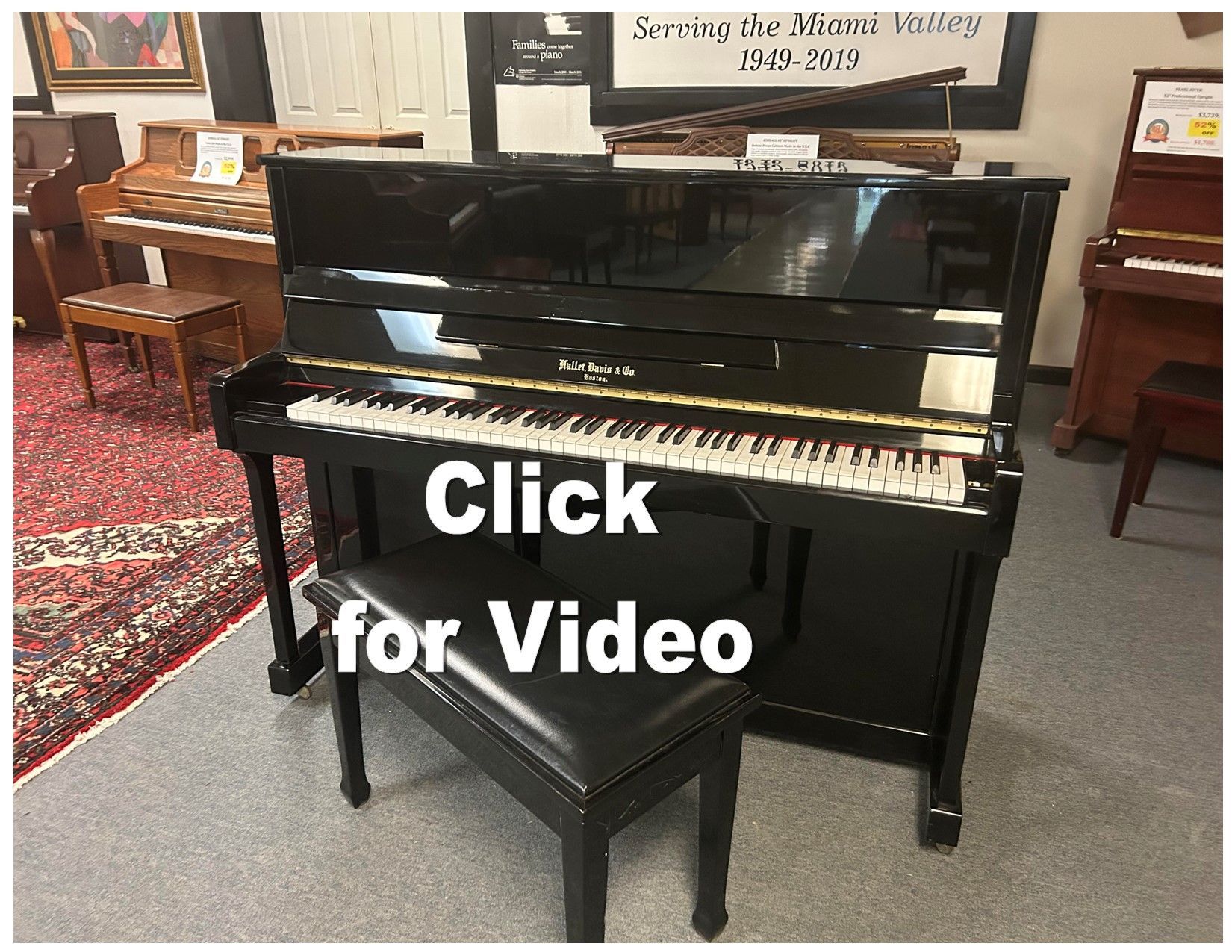 A black upright piano is sitting in a room with a bench.