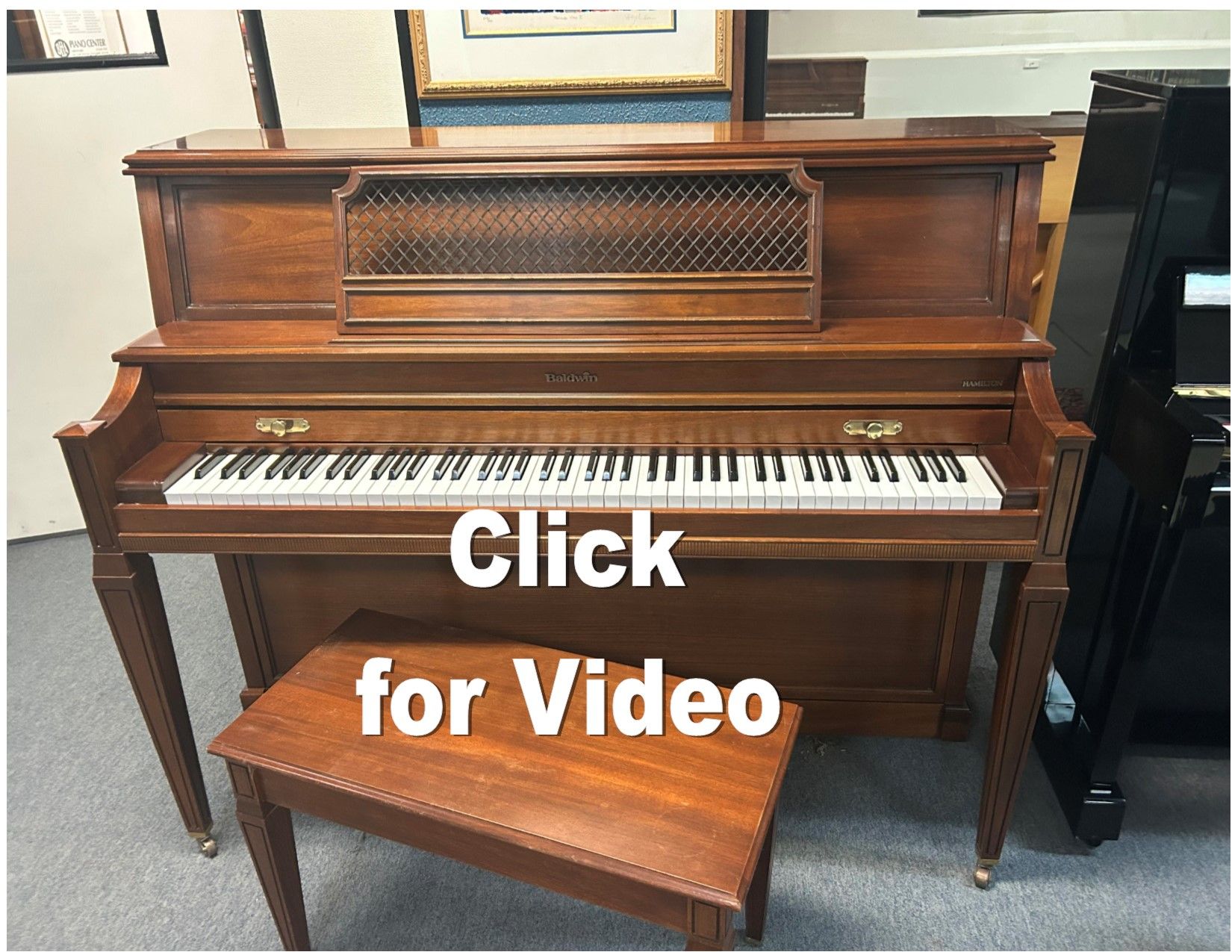 A piano with a bench next to it that says click for video