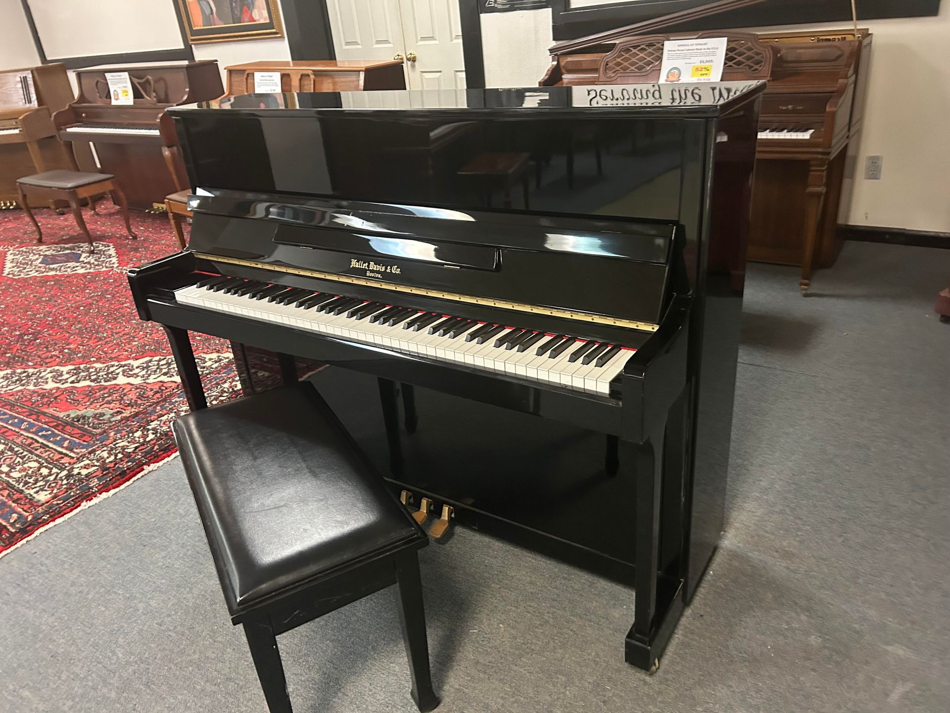 A black upright piano with a bench in a room.