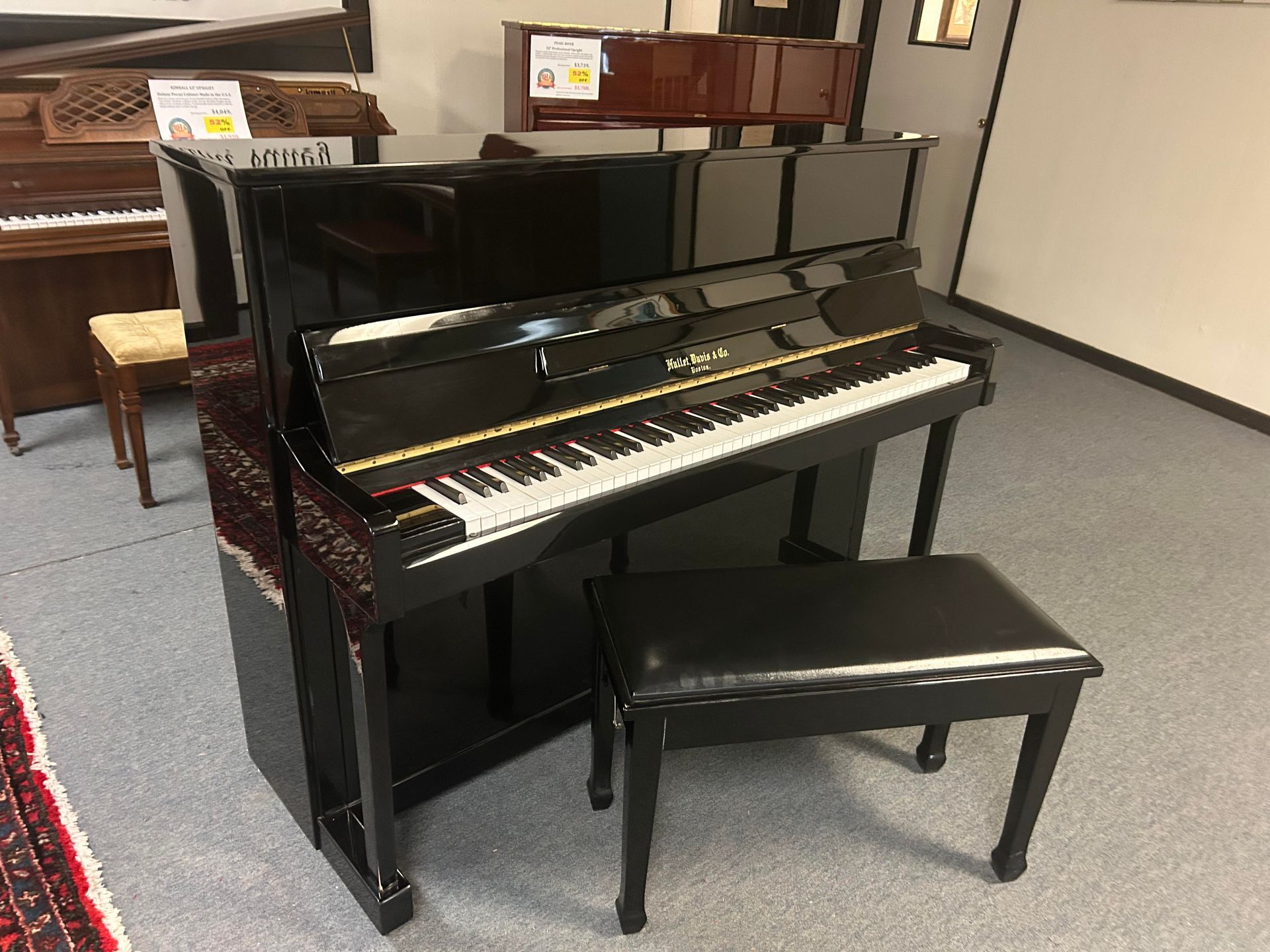 A black upright piano with a bench in a room.