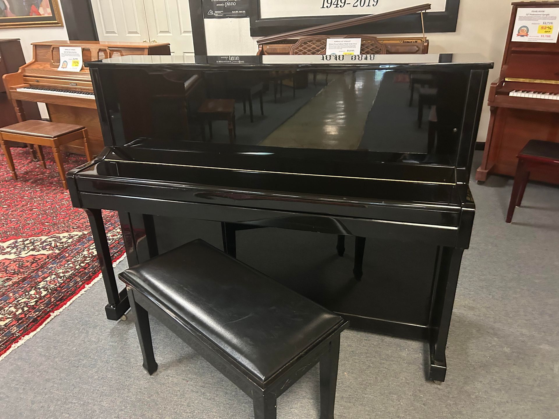 A black piano with a bench next to it in a room.