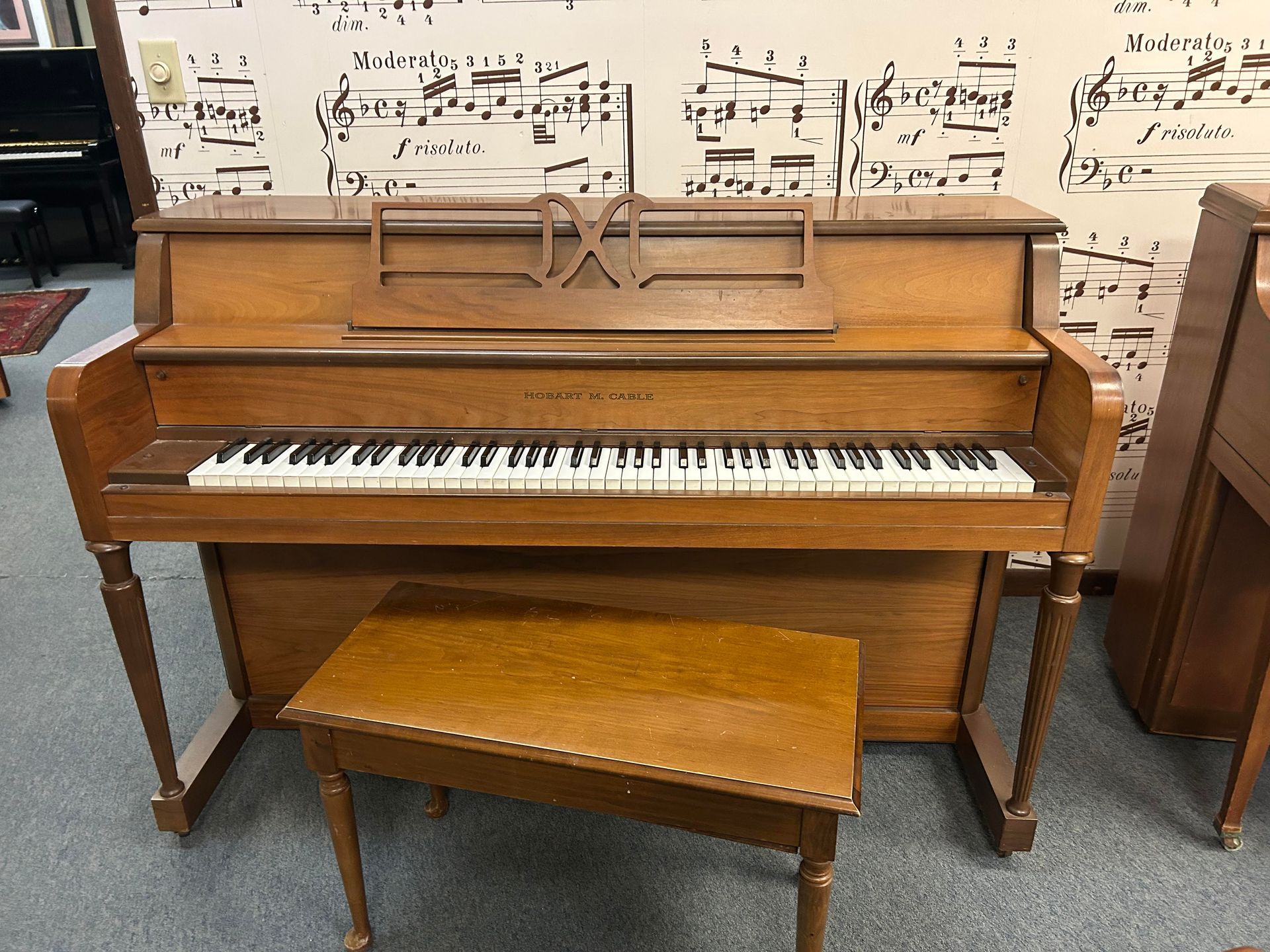 A piano is sitting in front of a wall with sheet music on it.