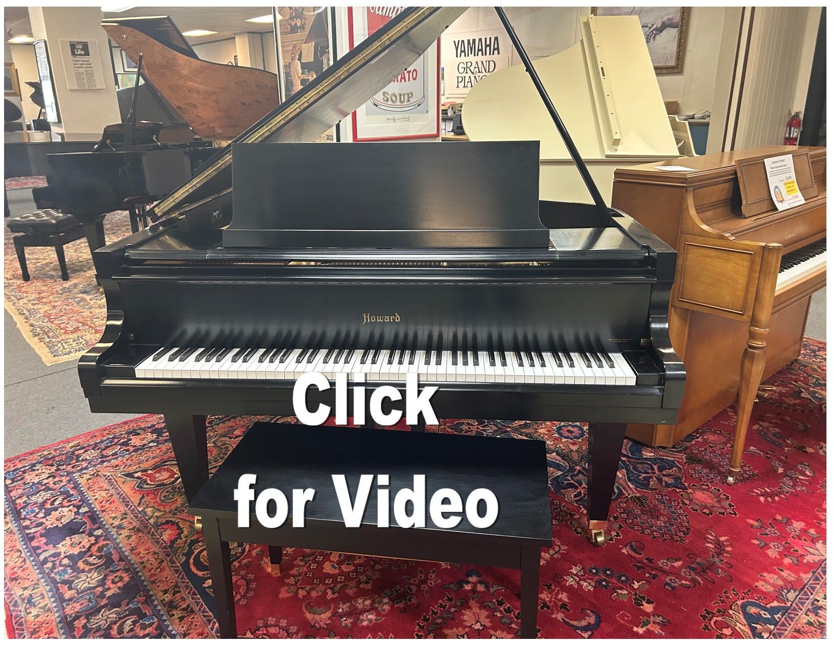 A black grand piano with music stand and bench in a showroom, with a