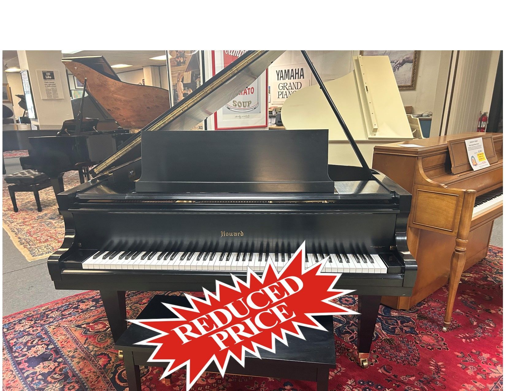 A black grand piano with music stand and bench in a showroom, with a