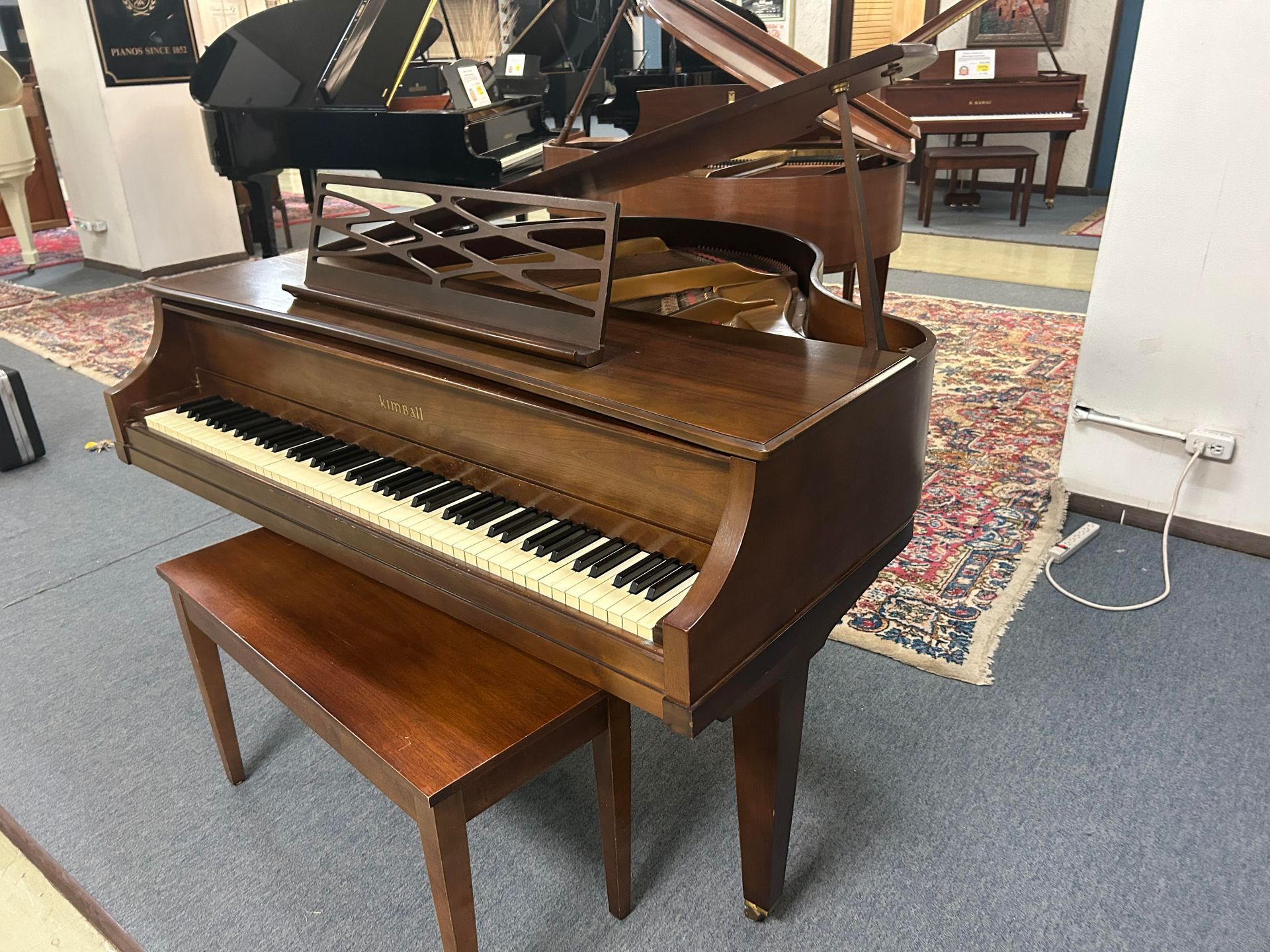 A grand piano is sitting in a room next to a bench.