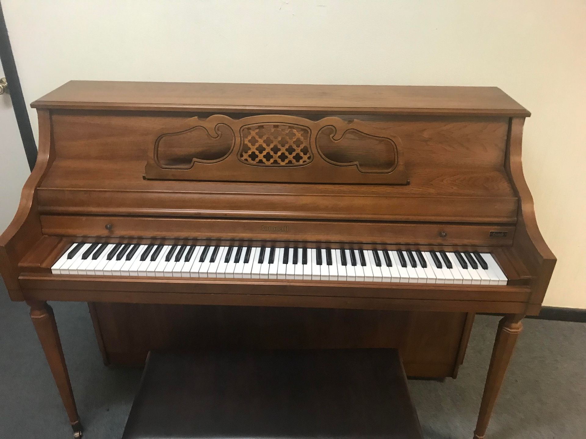 A wooden piano with a stool underneath it