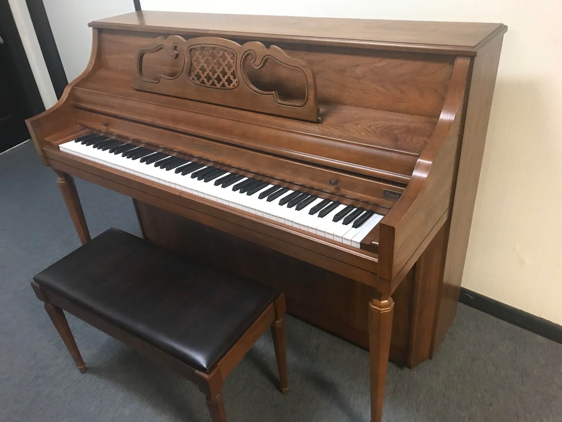 A piano with a bench next to it in a room