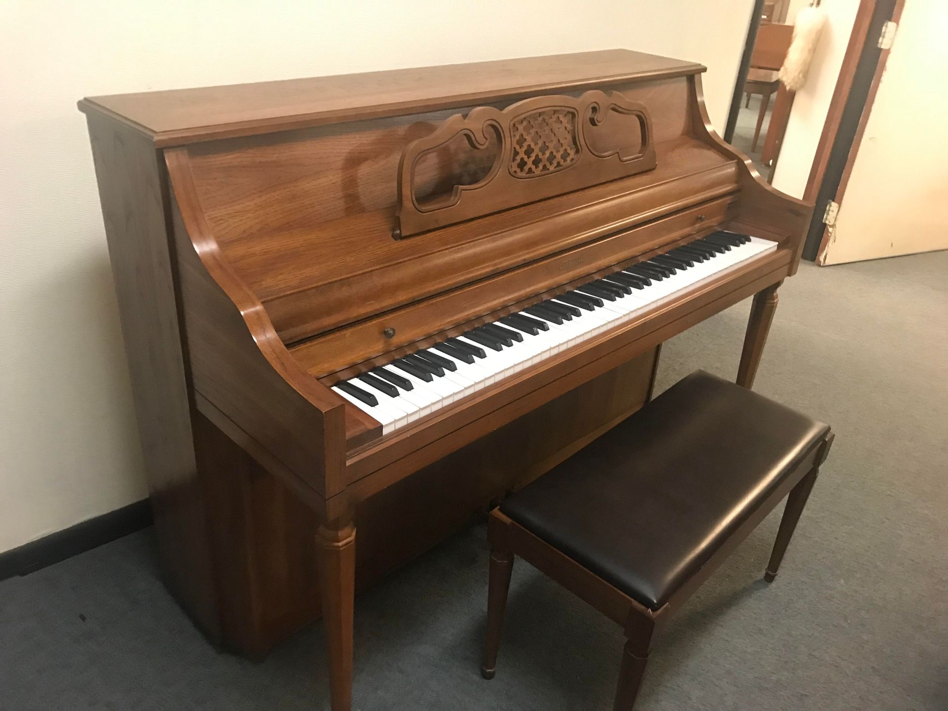 A piano with a bench next to it in a room.