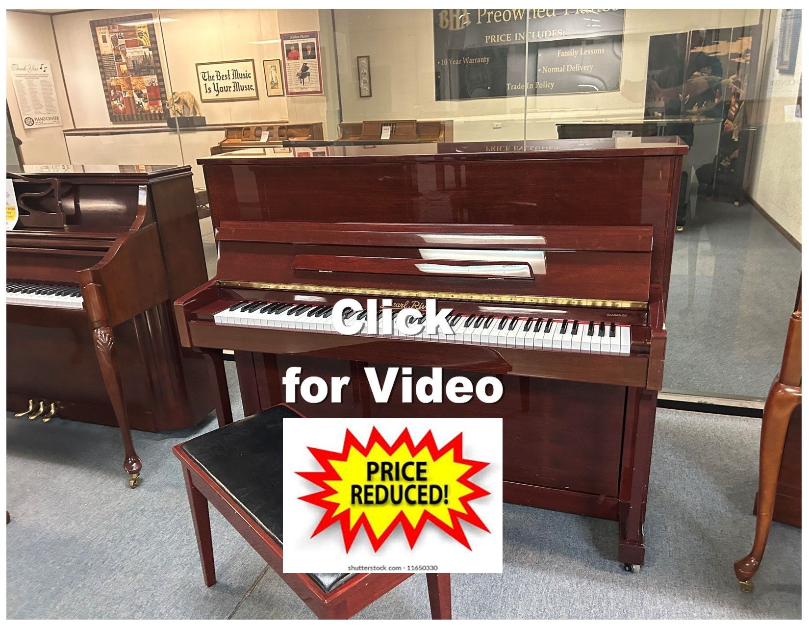 A reddish-brown upright piano with a bench in a showroom. 