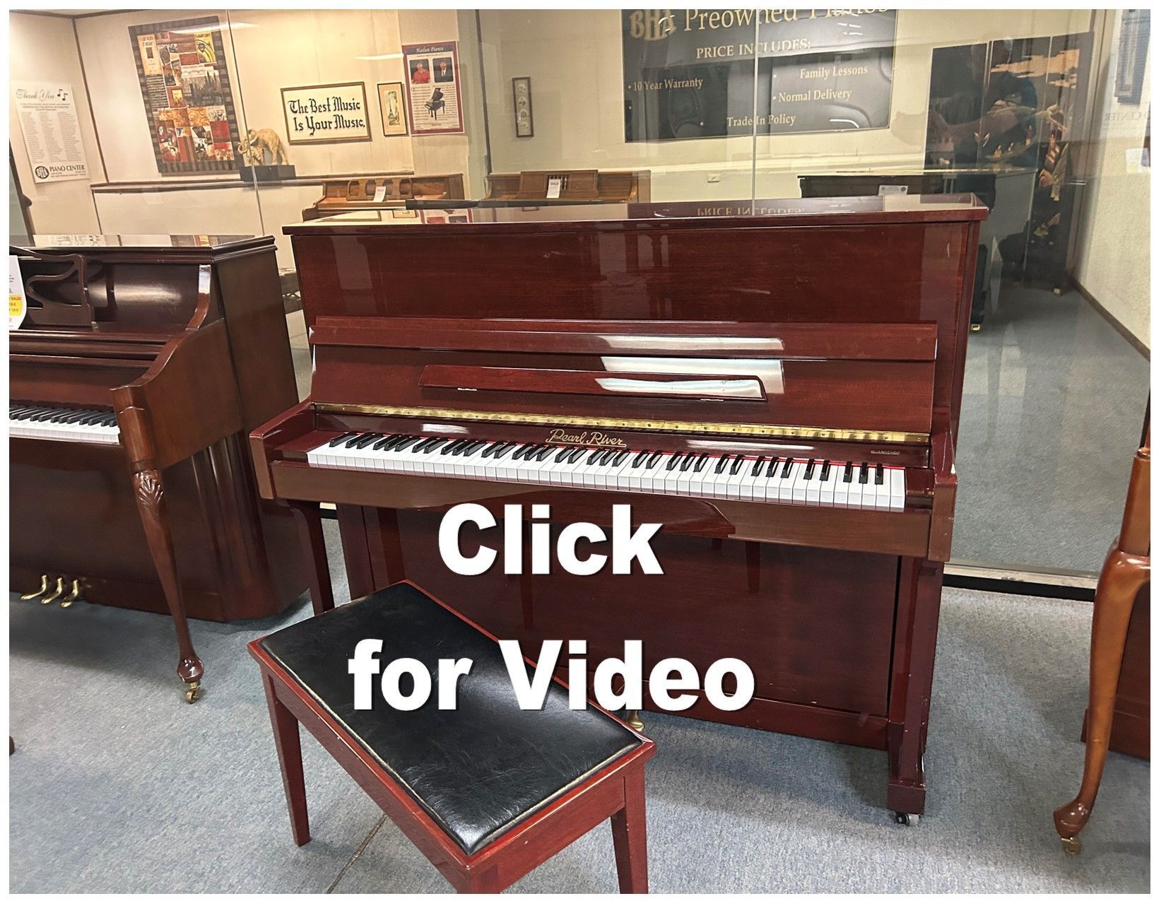 A reddish-brown upright piano with a bench in a showroom.