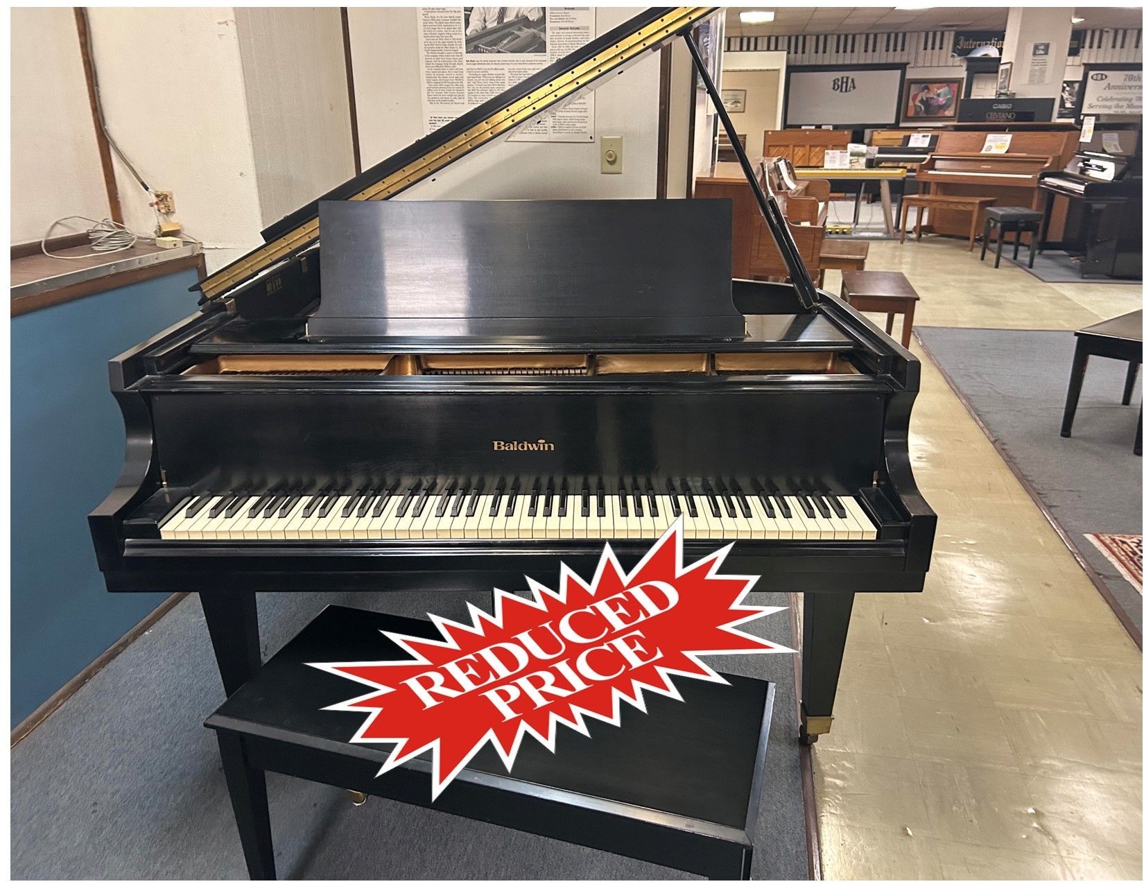 Black grand piano in a music store, with a bench.