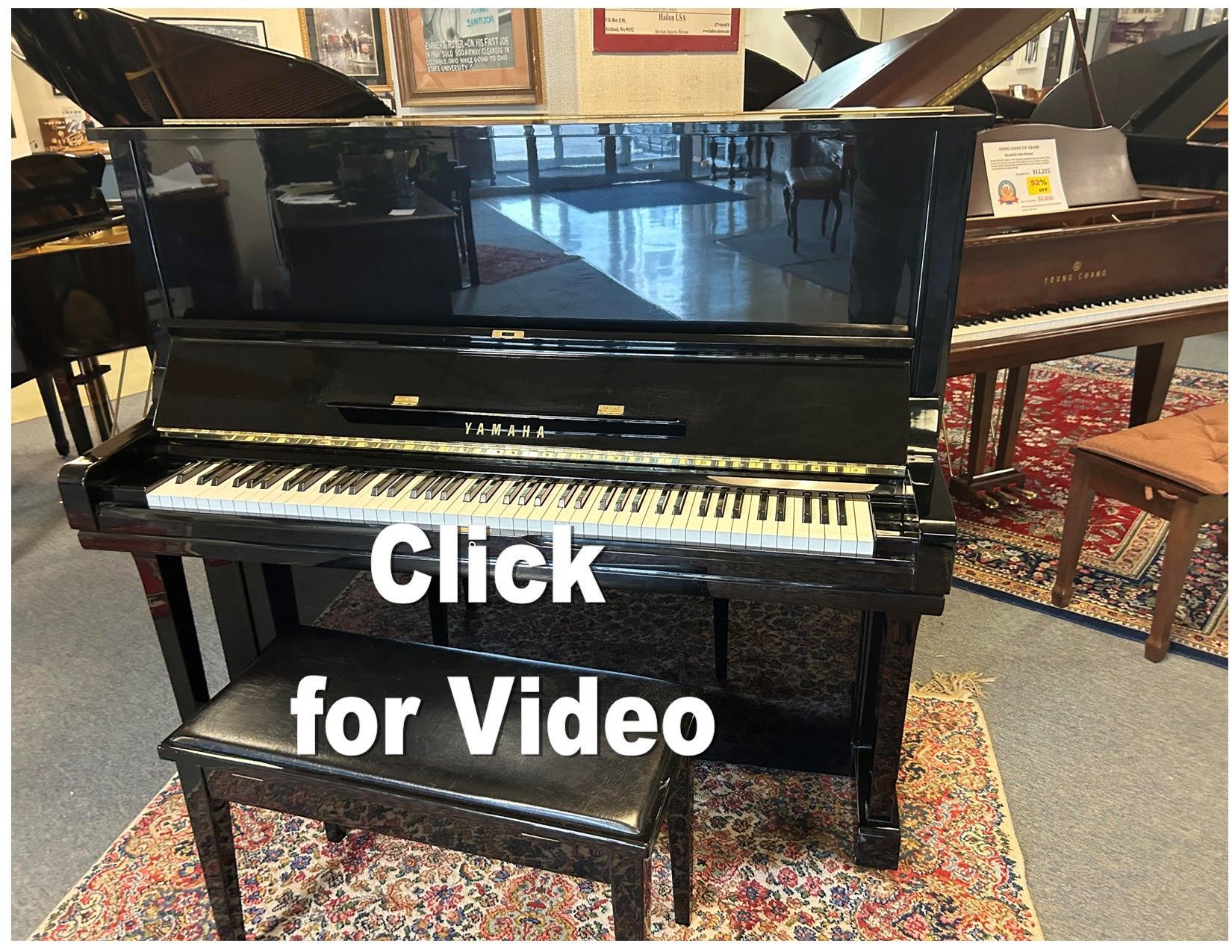 A black upright piano with a bench in a showroom, with