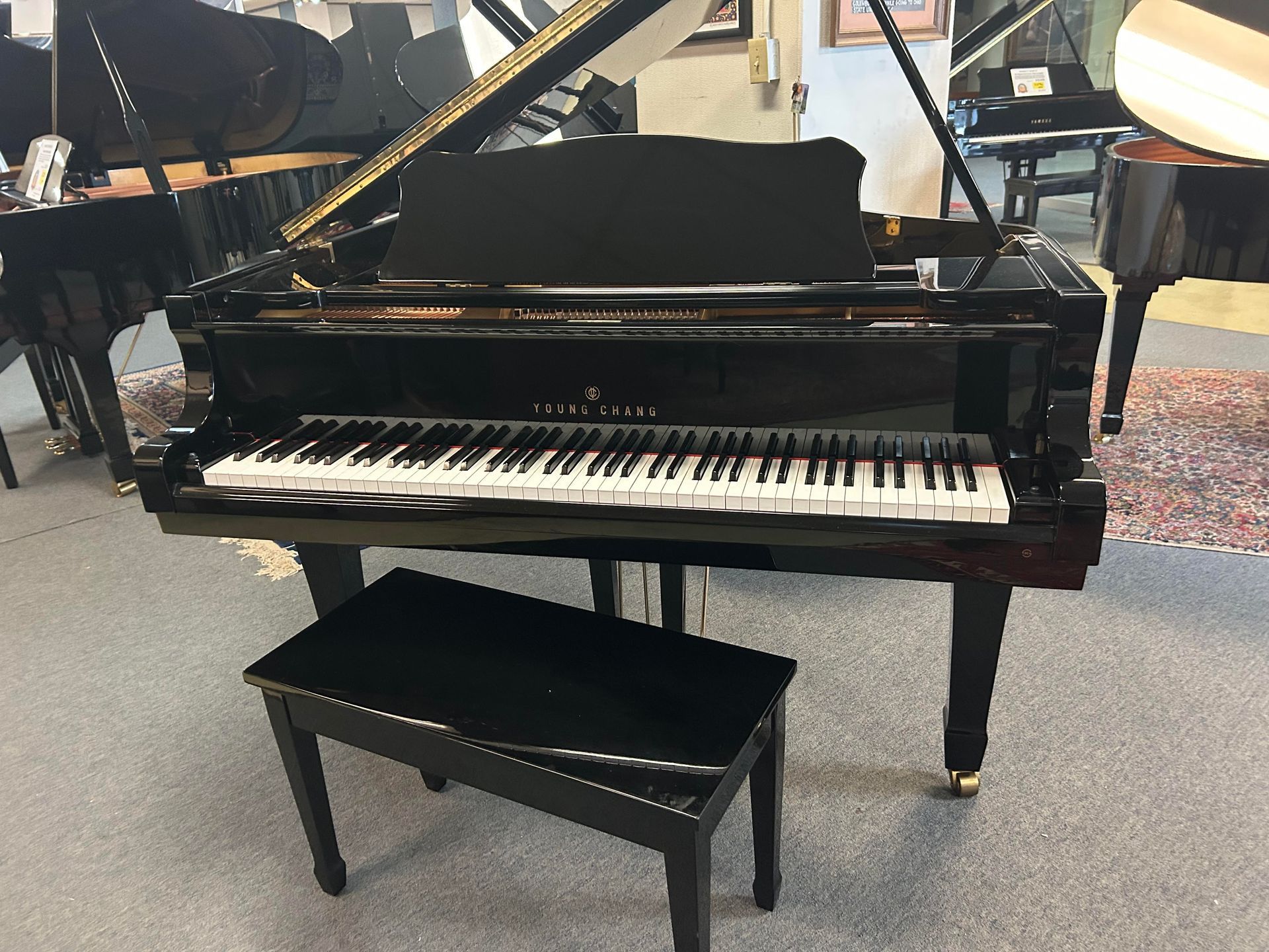 A black grand piano with a bench next to it in a room.