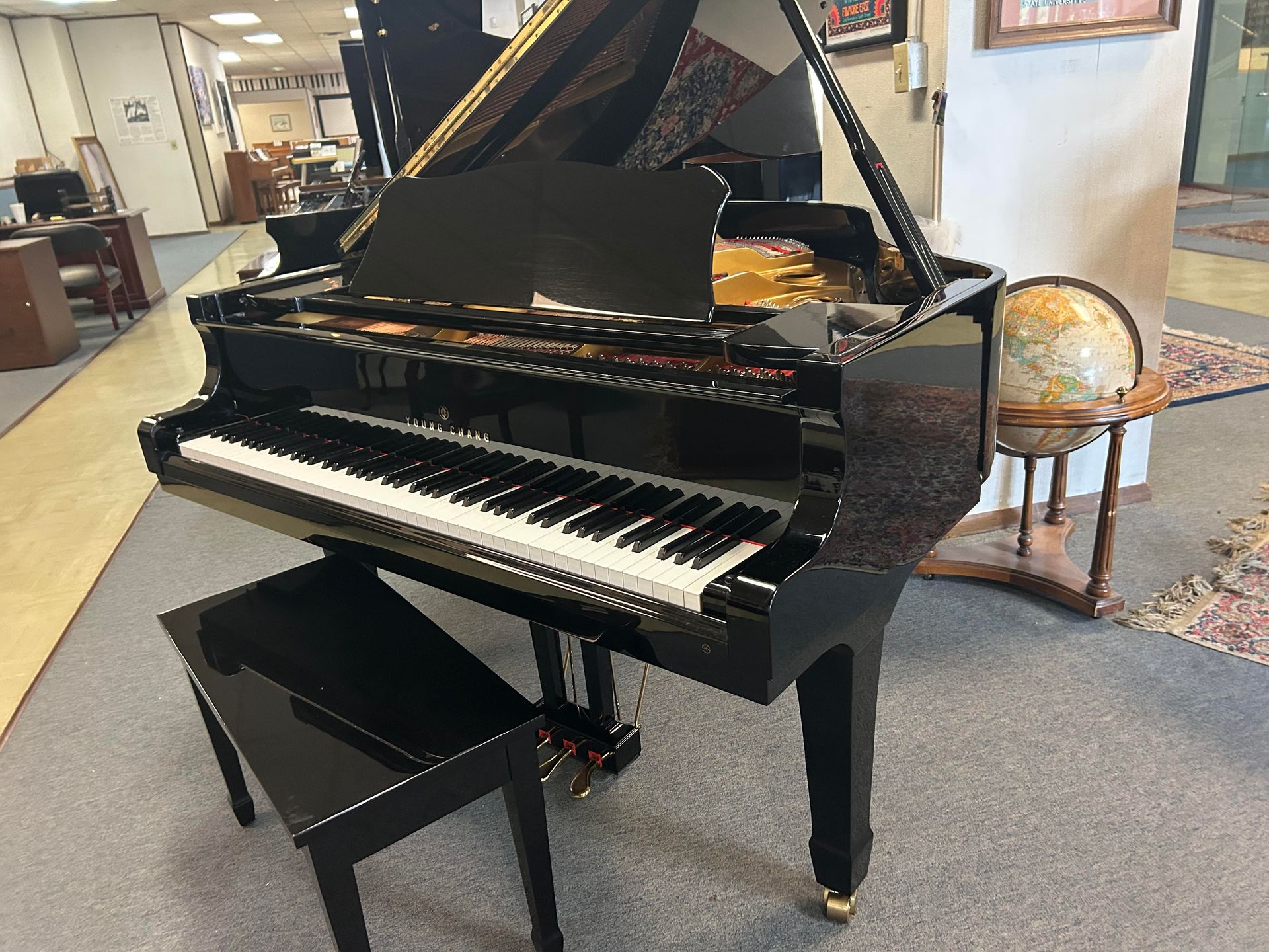 A black grand piano is sitting in a room next to a bench.