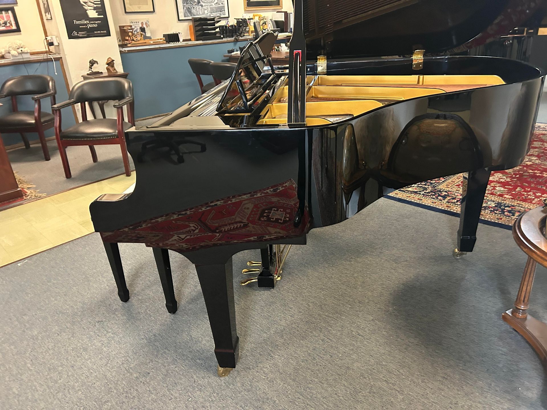 A black grand piano is sitting in a room with chairs.