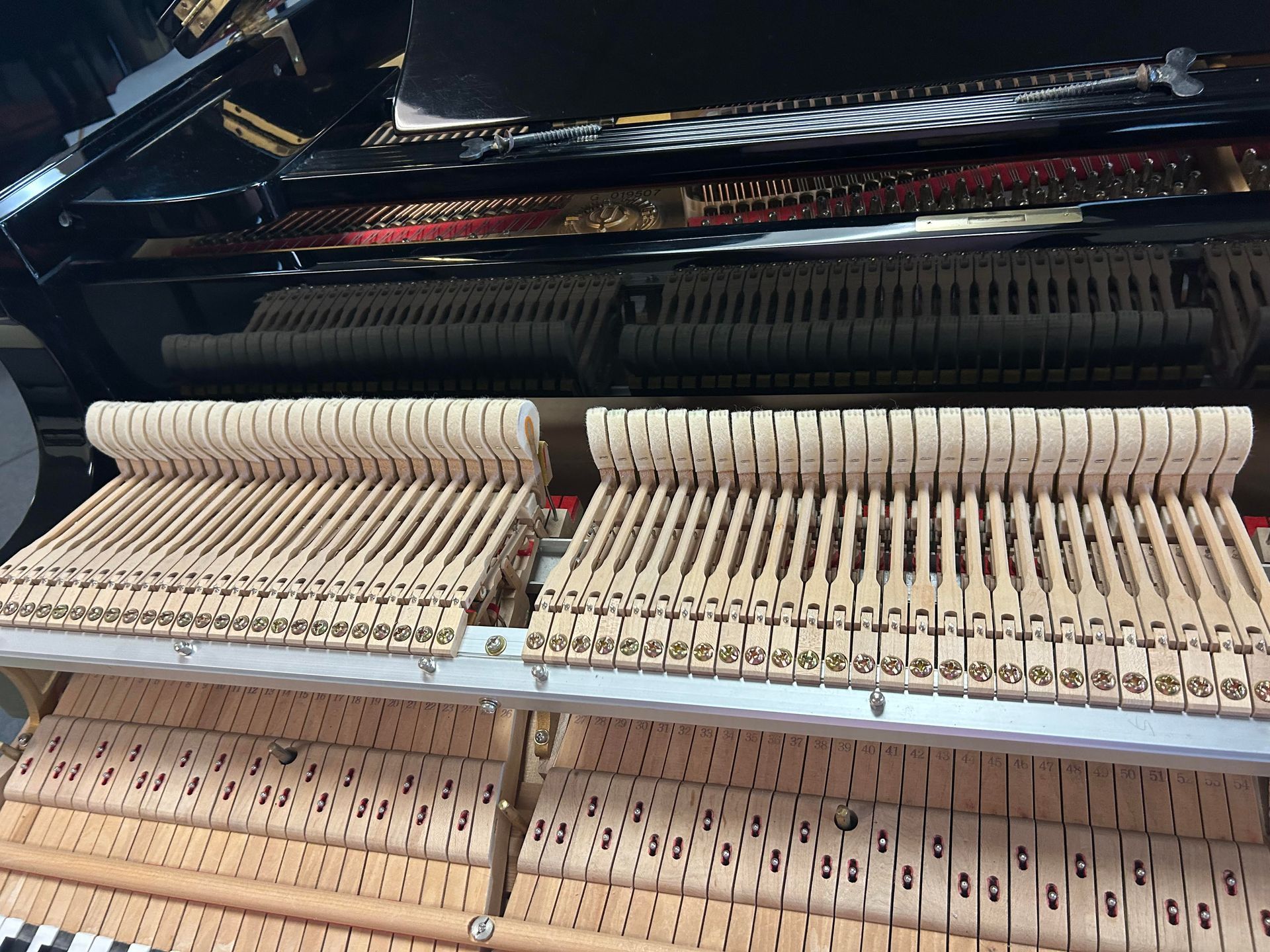 A close up of the inside of a piano showing the keys