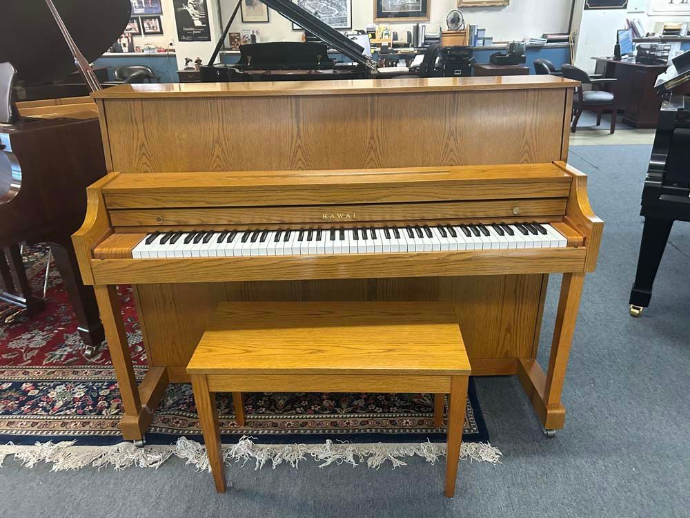 Oak upright piano with bench in a showroom.