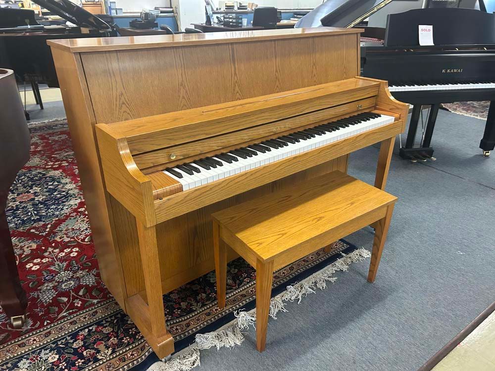 Upright wooden piano with bench on a patterned rug.