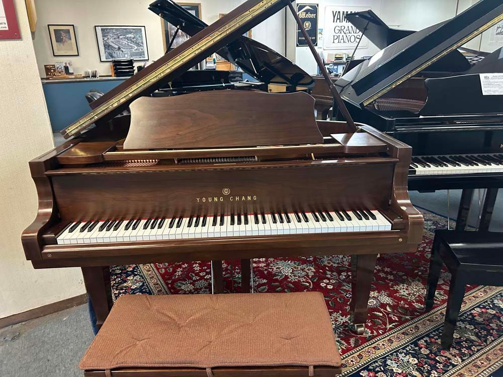 A grand piano is sitting in a room with other pianos.