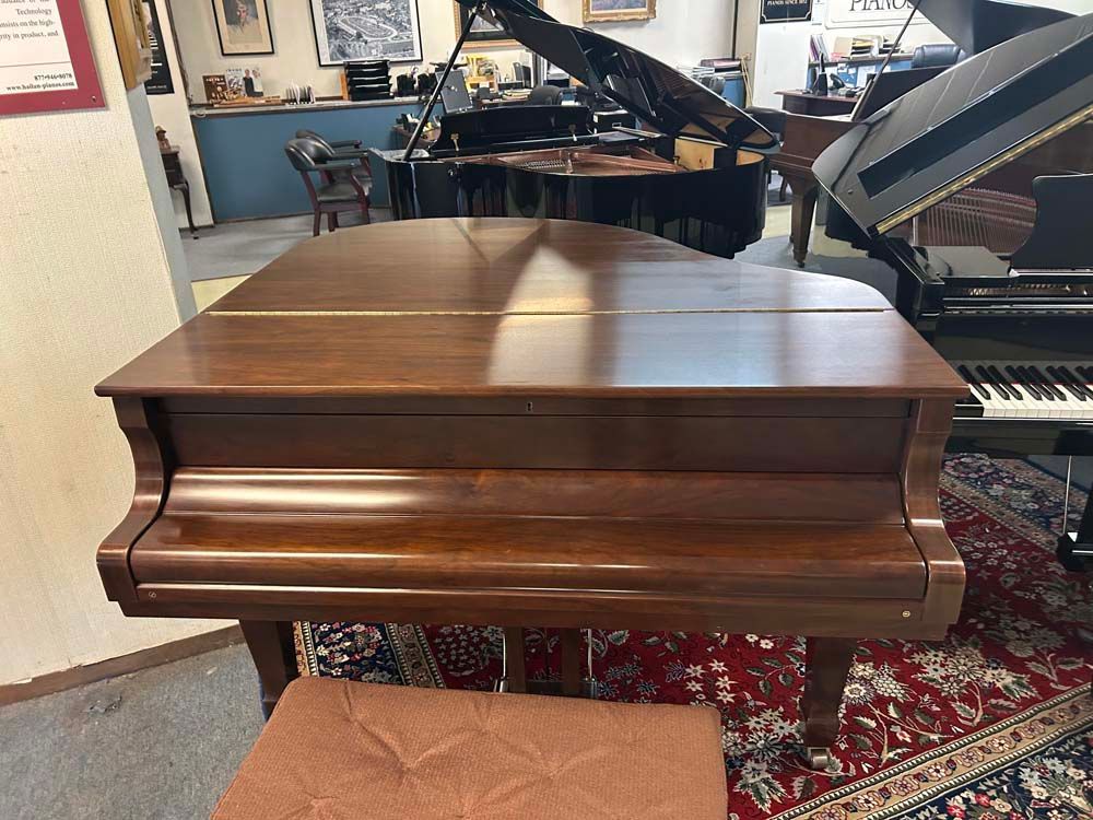 A piano is sitting on a stool in a room with other pianos.