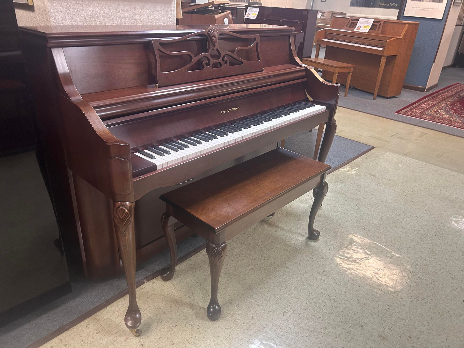 Wooden upright piano with bench in a room.