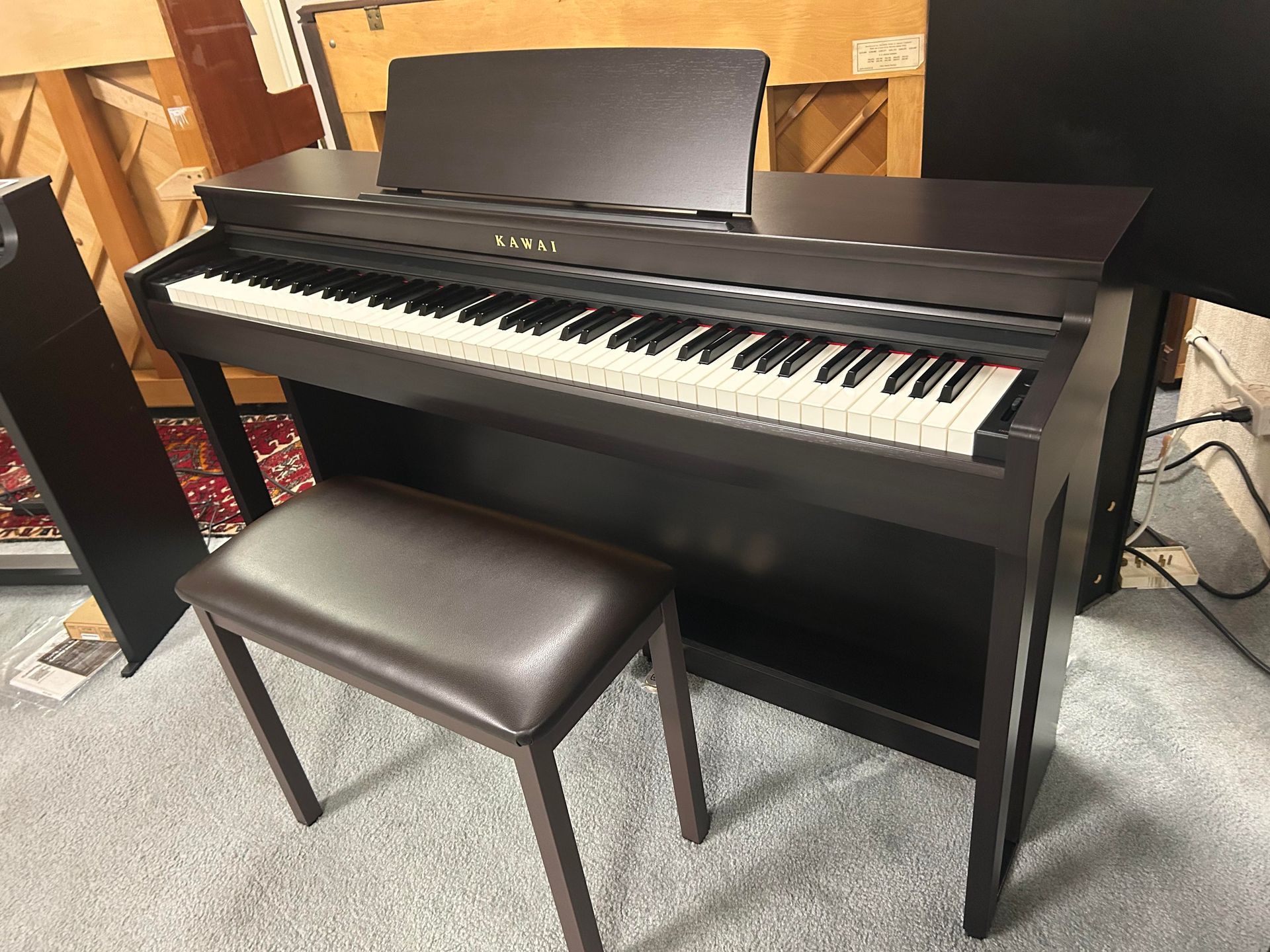 Dark brown Kawai digital piano with a matching stool in a room.