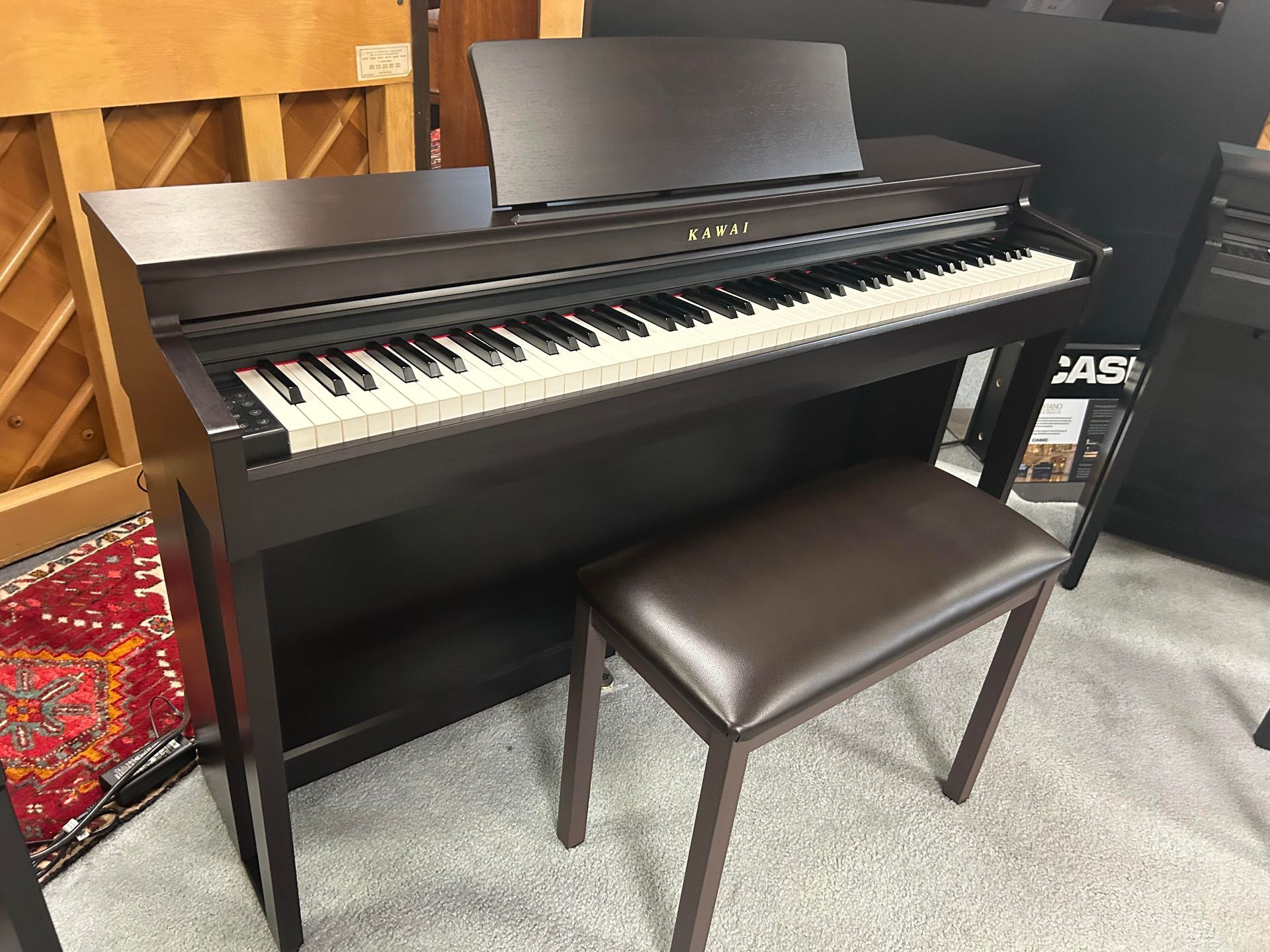 Dark brown digital piano with a matching stool, in a shop.