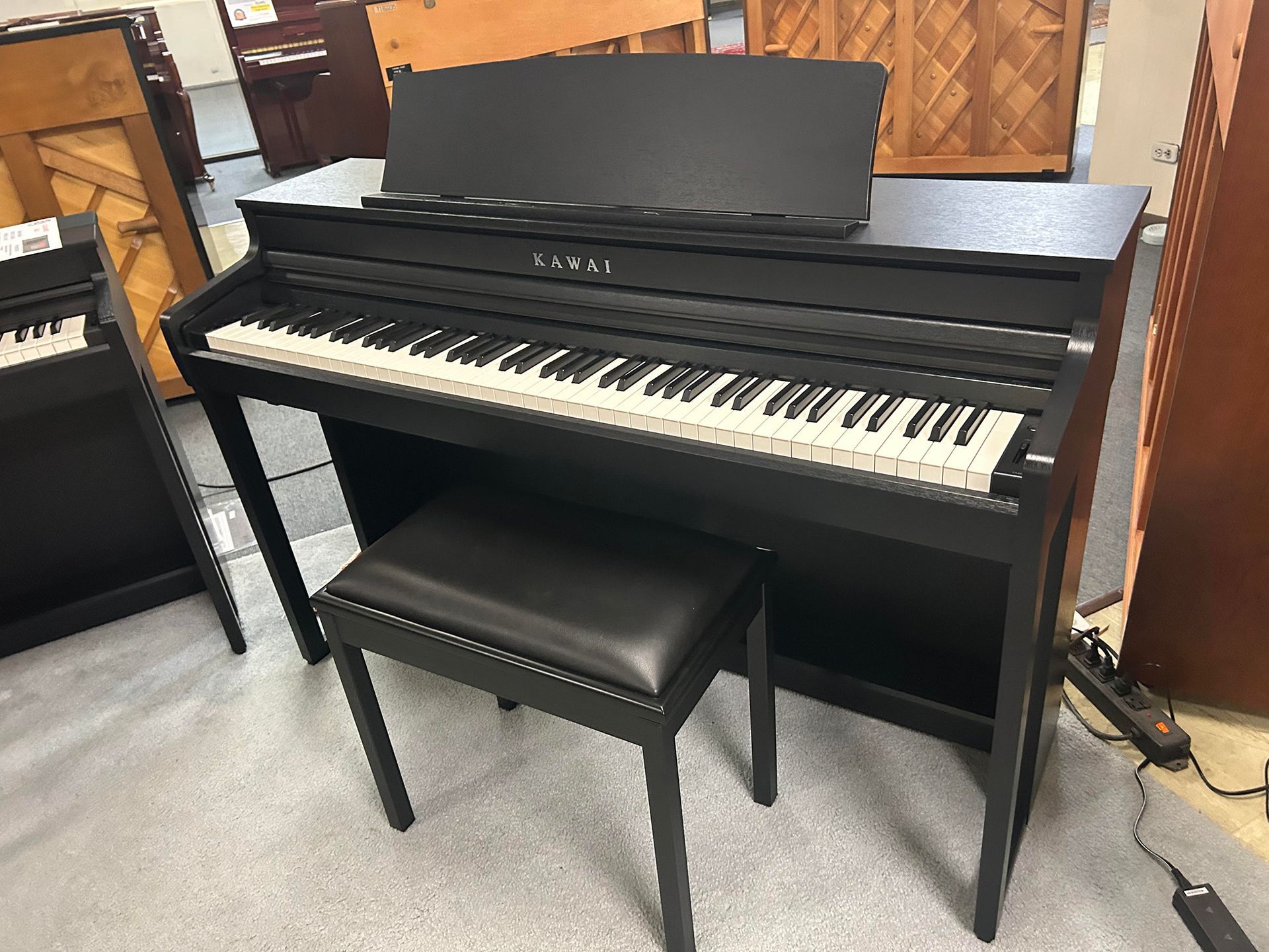 Black Kawai digital piano with matching bench. Keyboard is white and black.