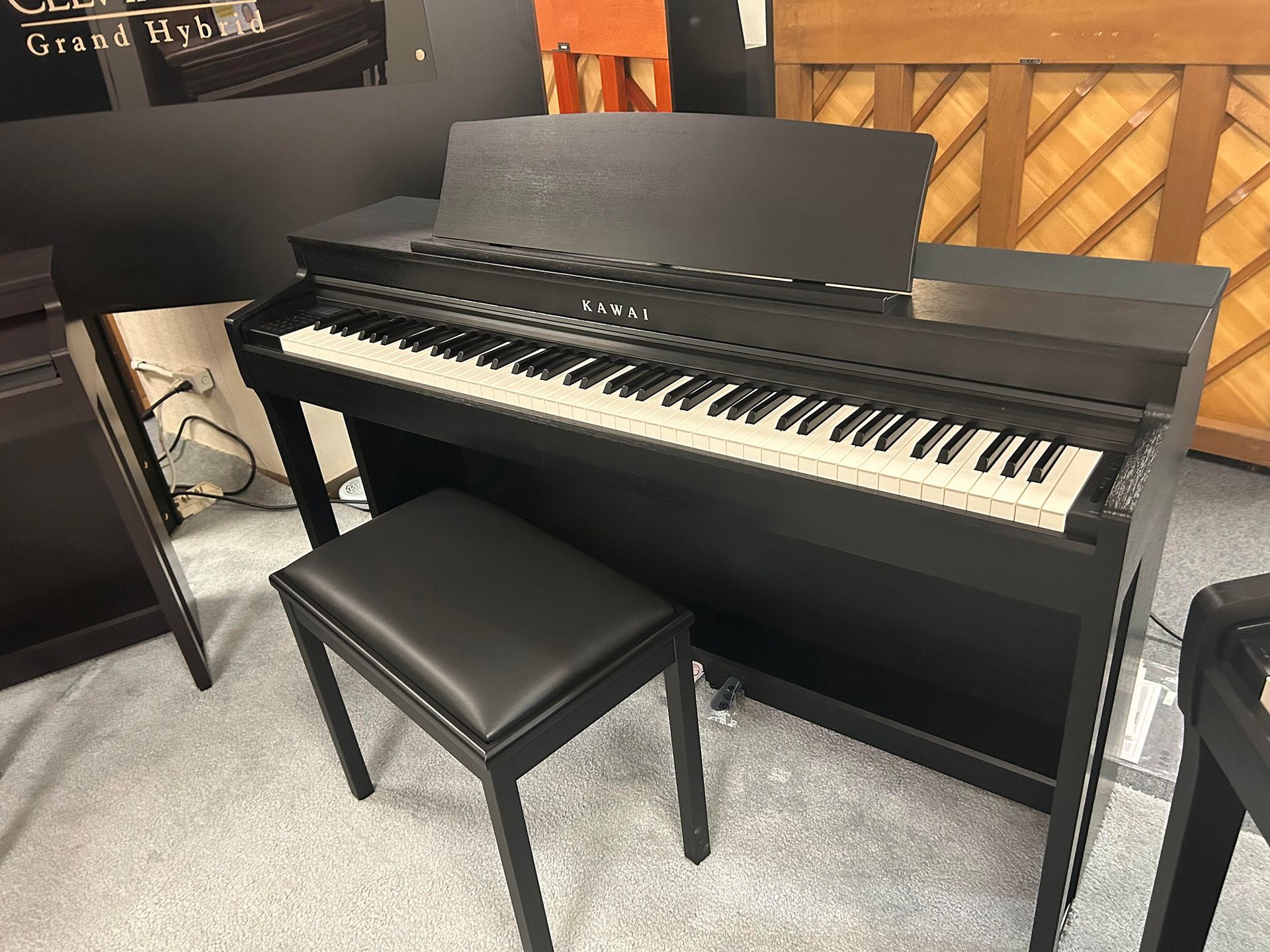 Black digital piano with a matching stool in a showroom.