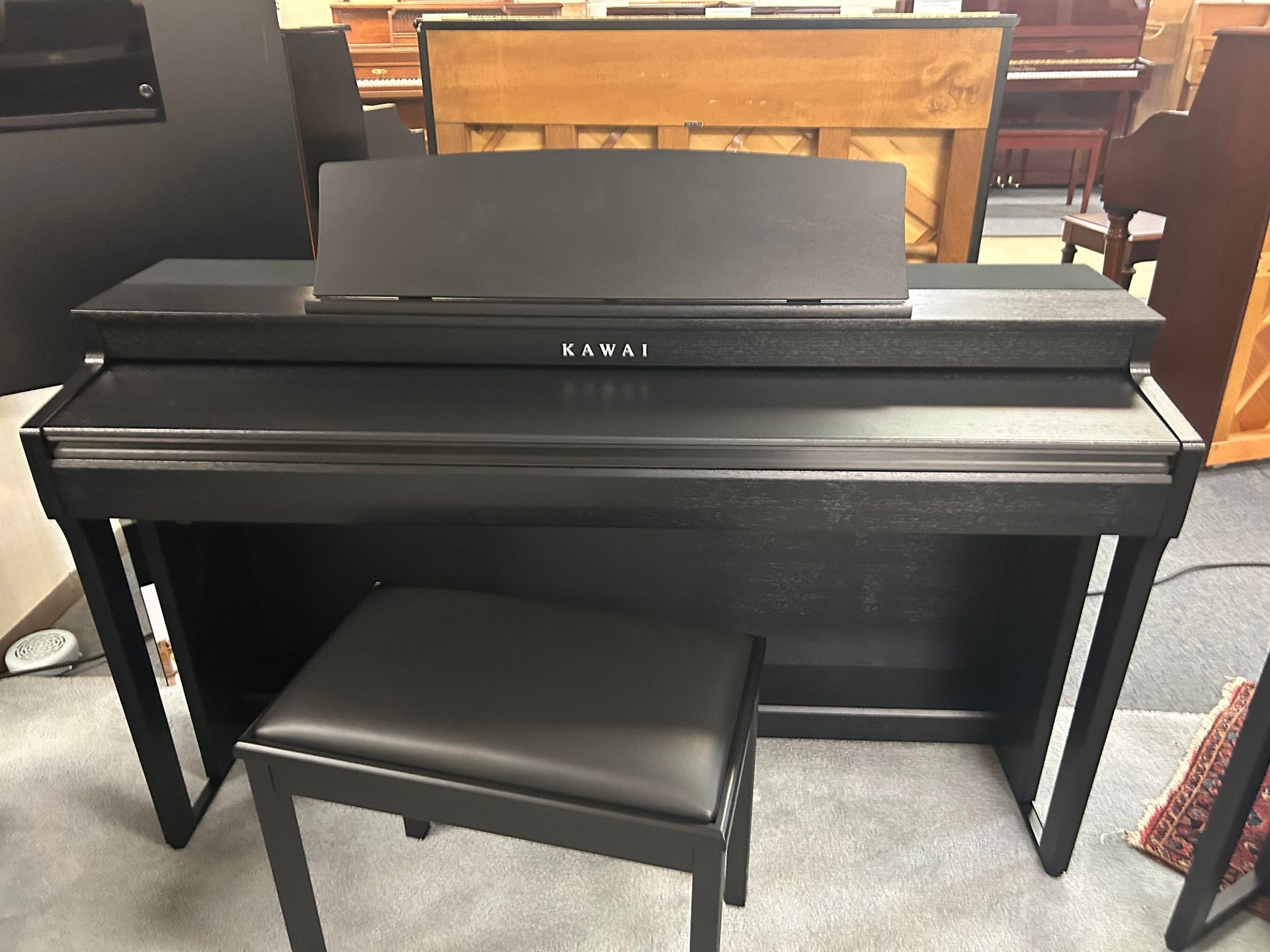 Black Kawai digital piano with matching bench.
