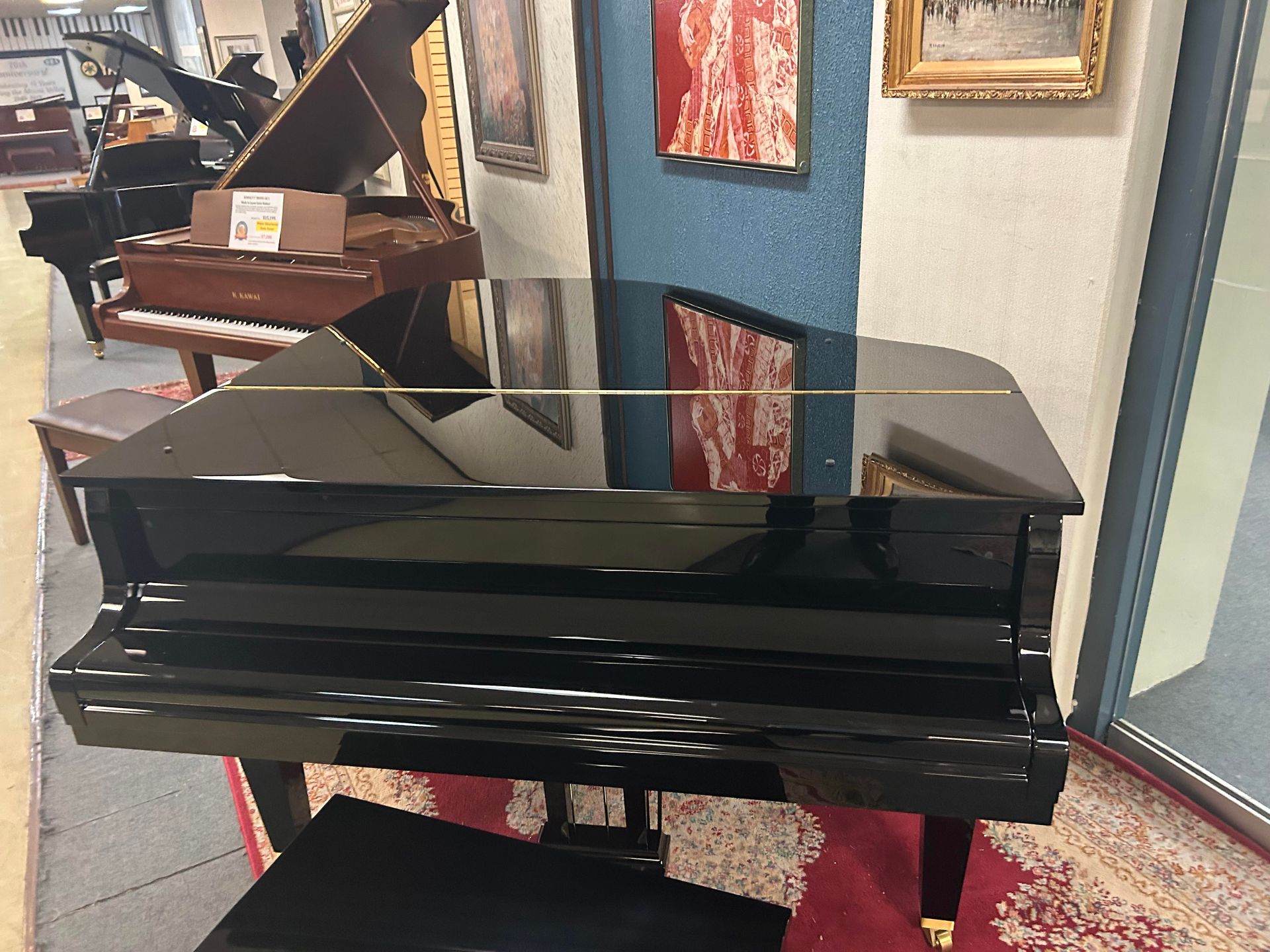 Black grand piano with glossy finish, displayed in a showroom.