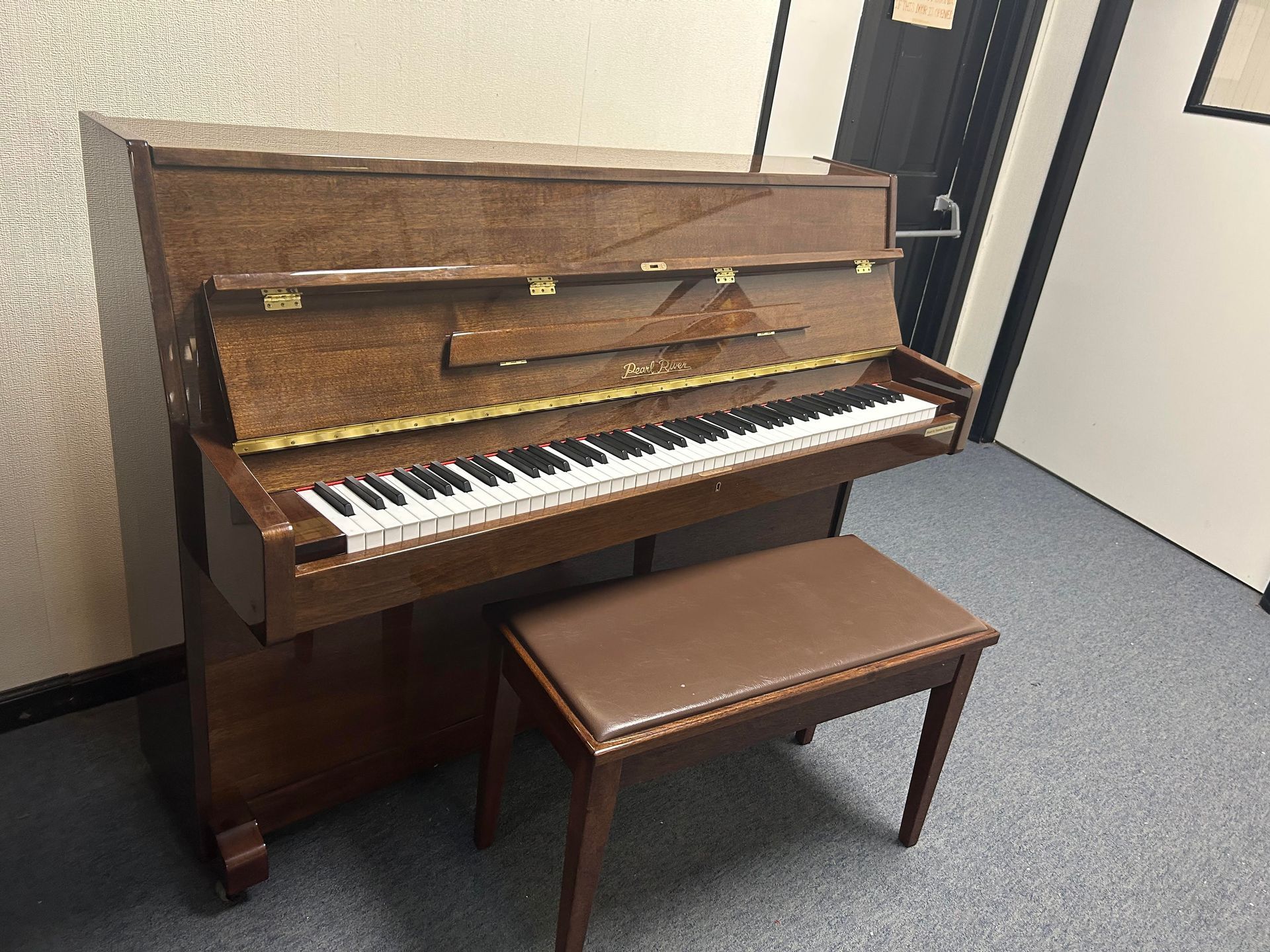 11351 - Pearl River 43, Brown upright piano with matching bench in a room.