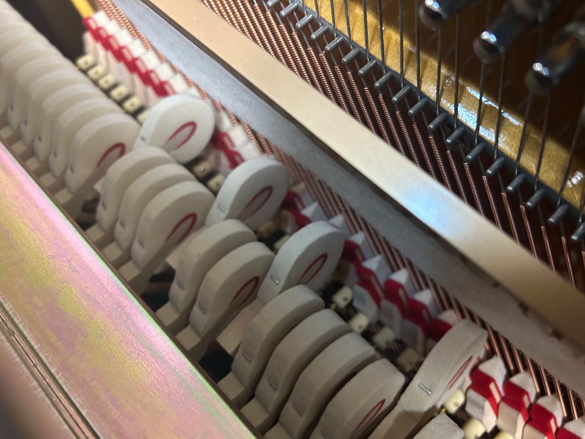 11351 - Pearl River 43, Inside of a piano: white hammers with red accents striking copper-colored strings.