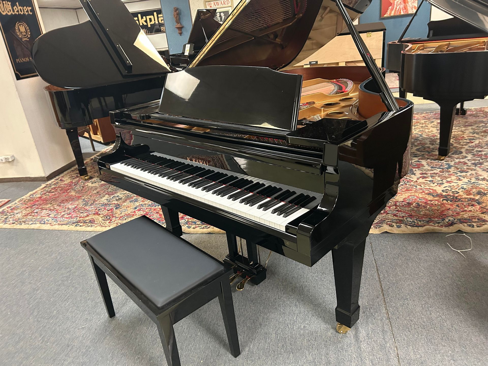 Black grand piano with music stand and bench in a showroom setting.