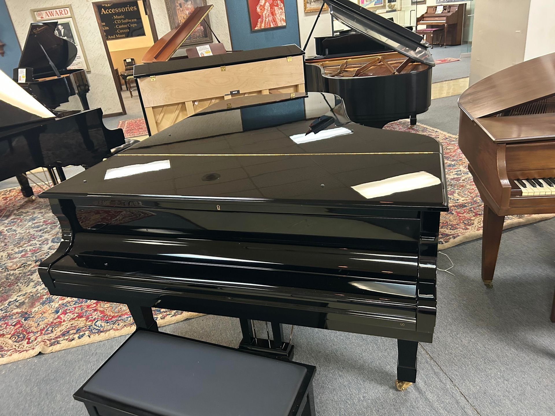 A glossy black grand piano in a showroom with other pianos.