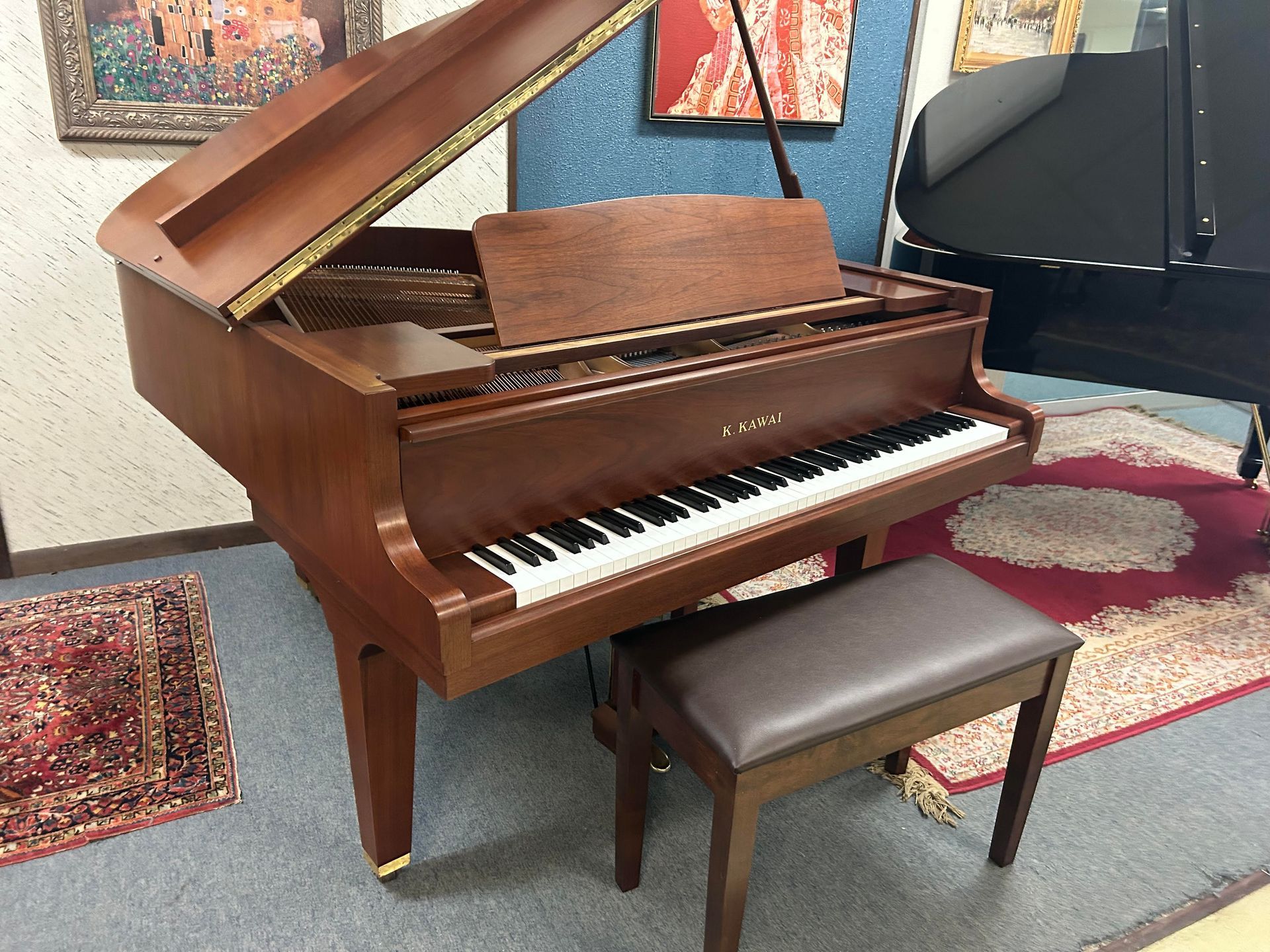 A grand piano is sitting in a room next to a bench.