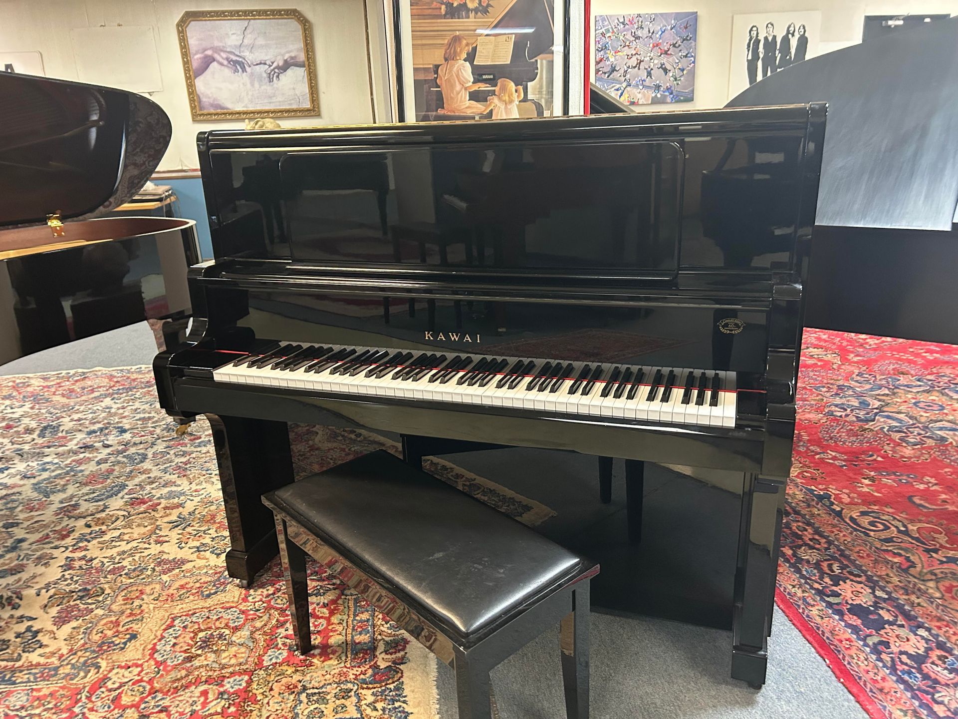 Black upright piano with bench on a patterned rug.