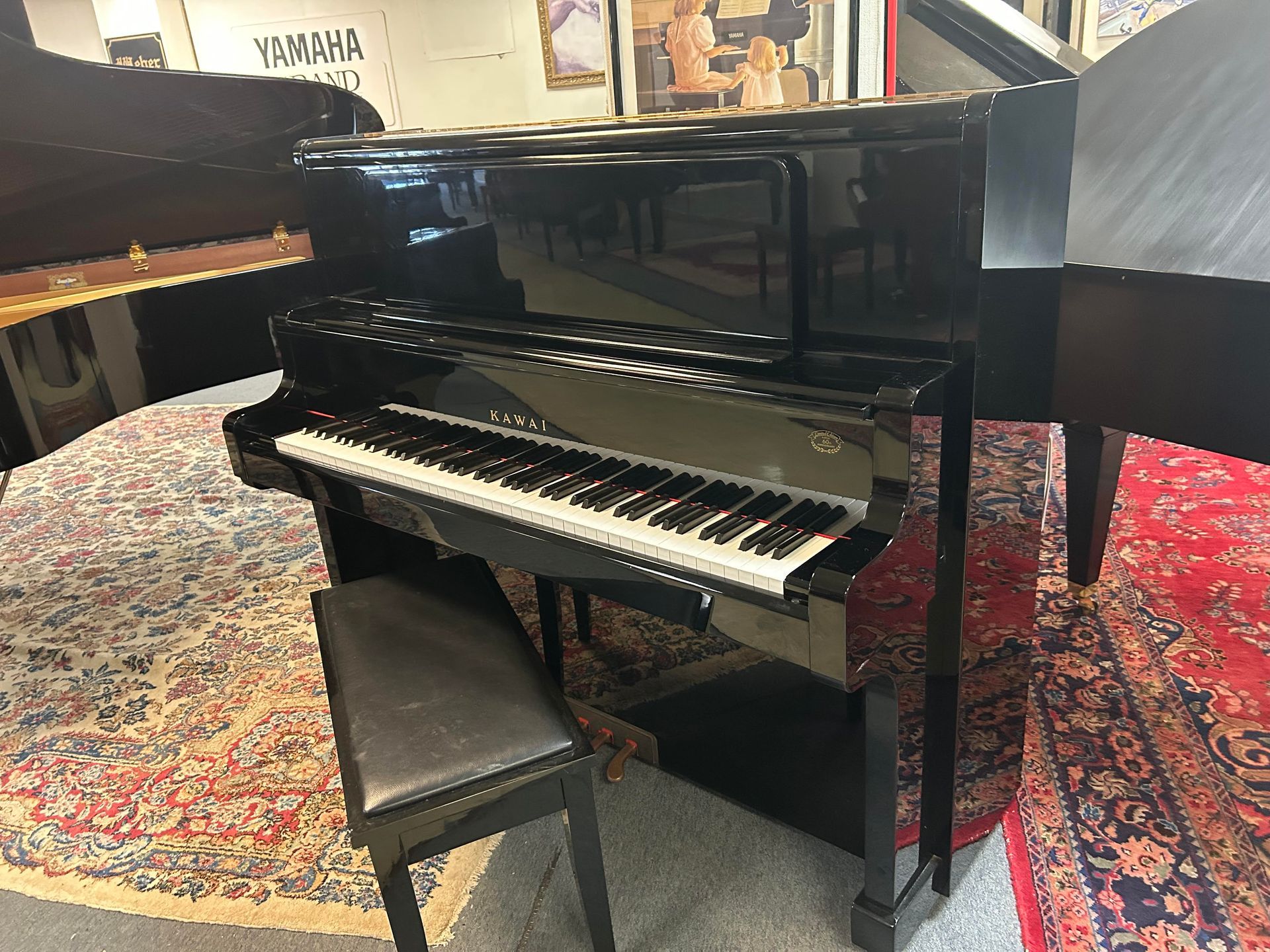 Black upright piano with bench on patterned rugs.
