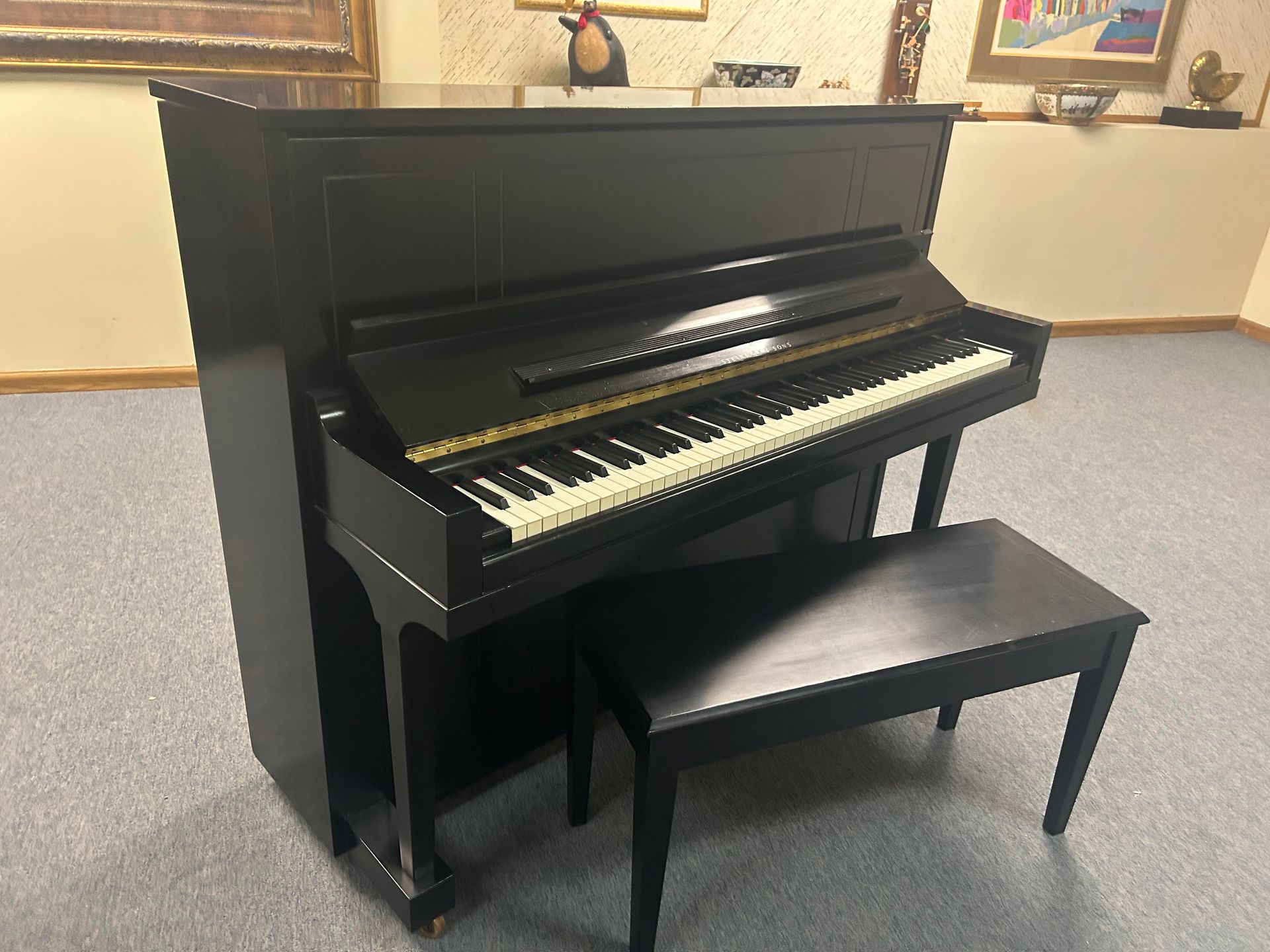 Black upright piano with matching bench in a room.