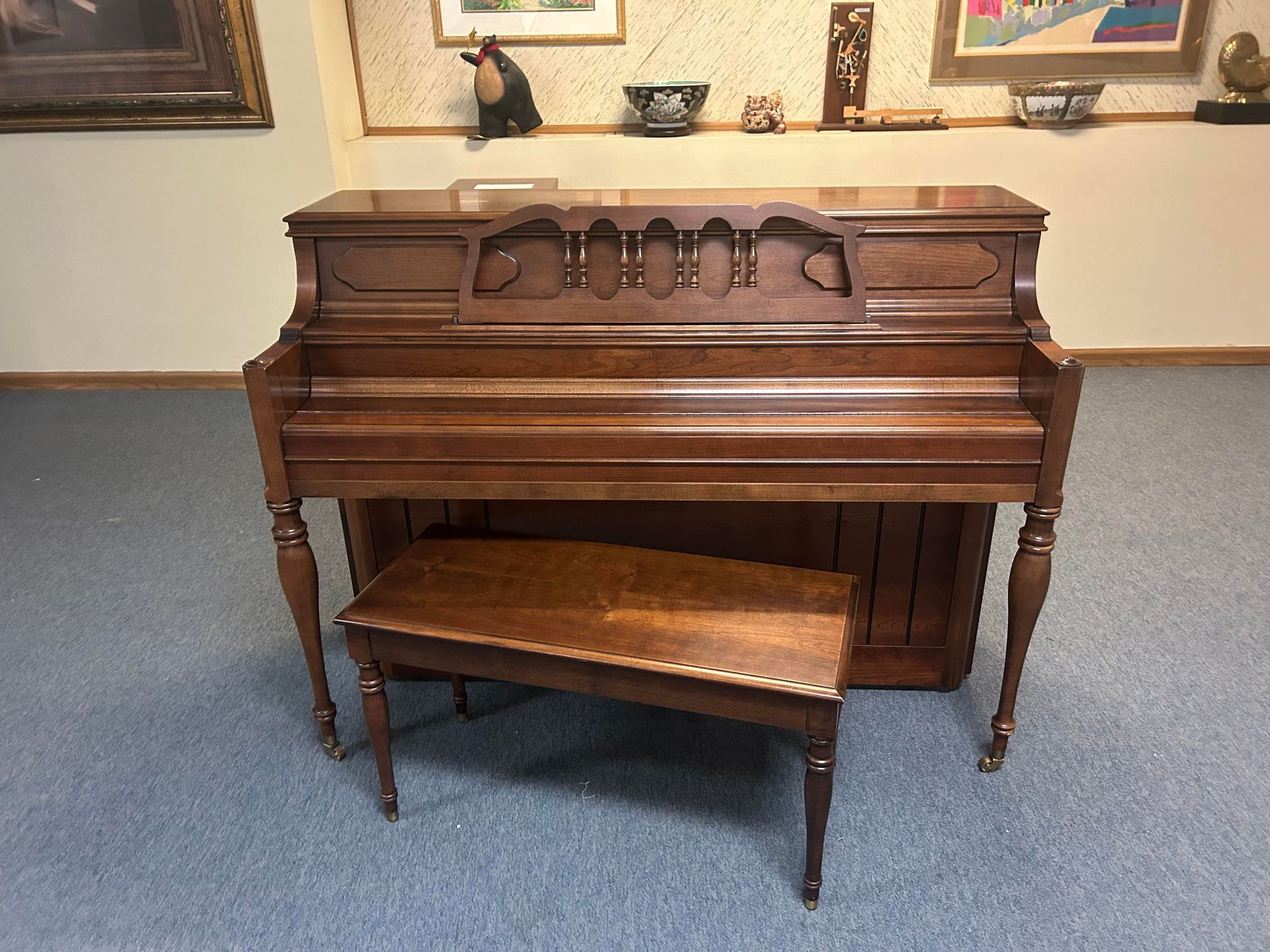 A piano is sitting in a room with a bench.