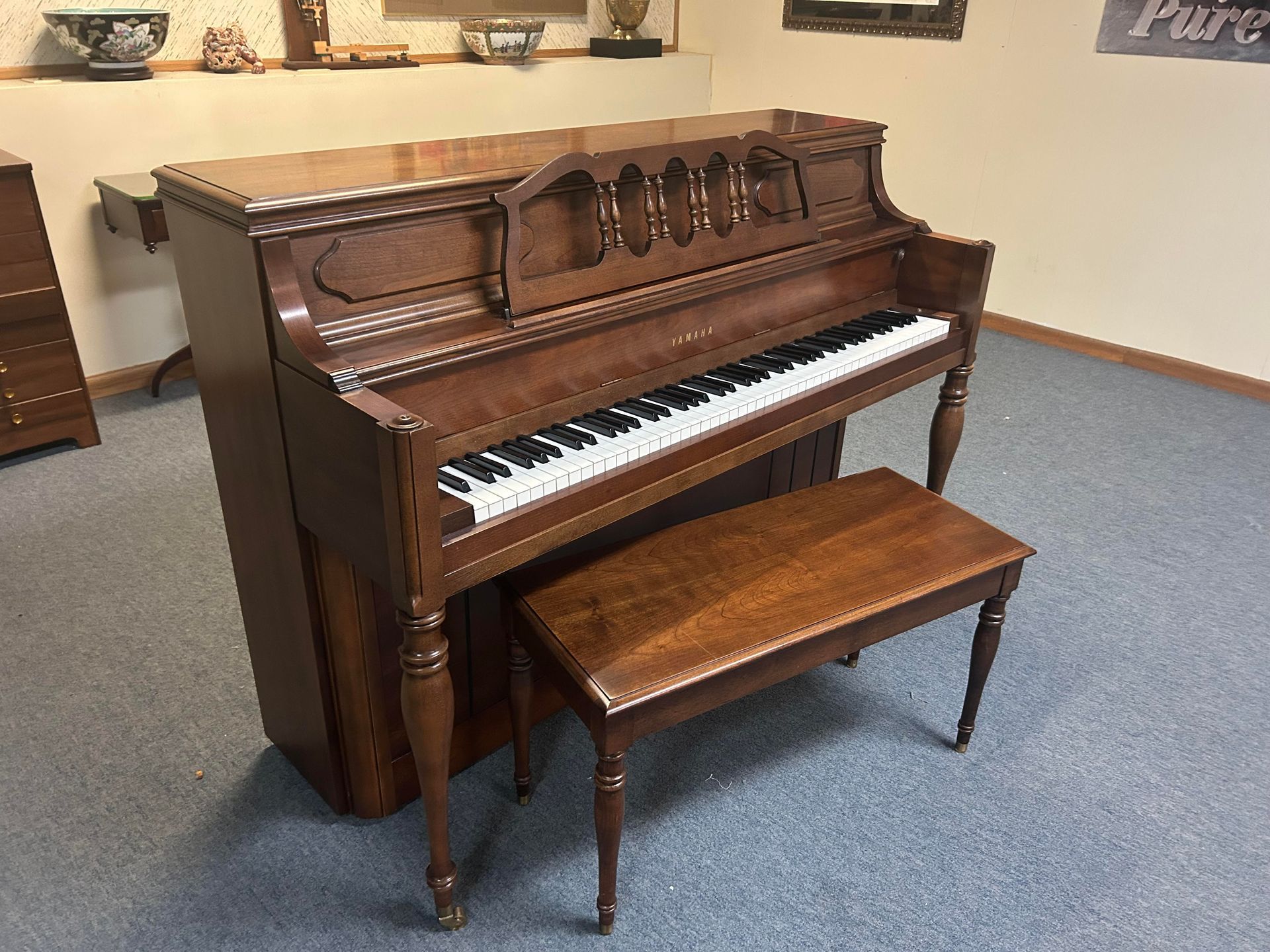 A piano is sitting in a room next to a bench.