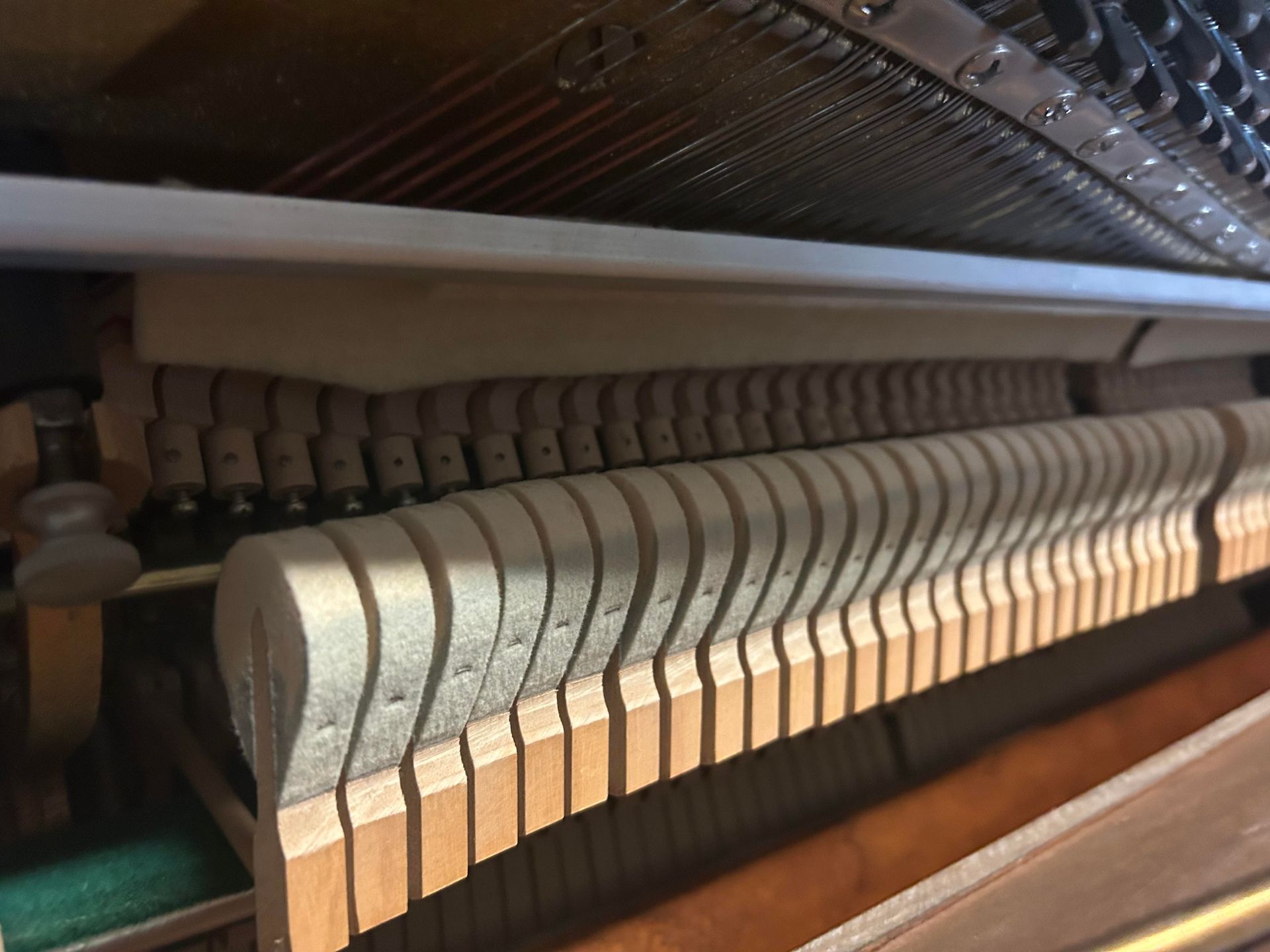 A close up of the inside of an upright piano.