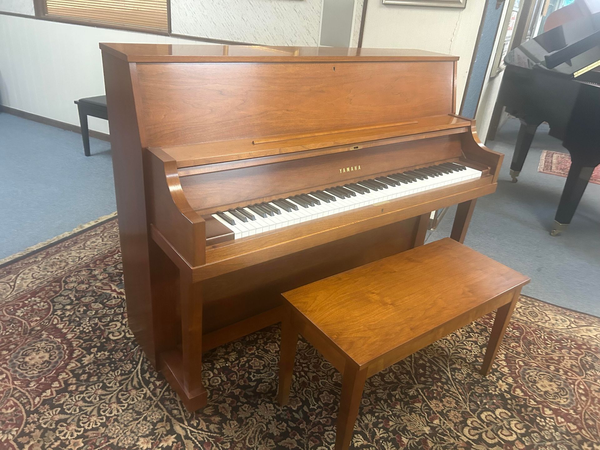A piano with a bench next to it in a room.