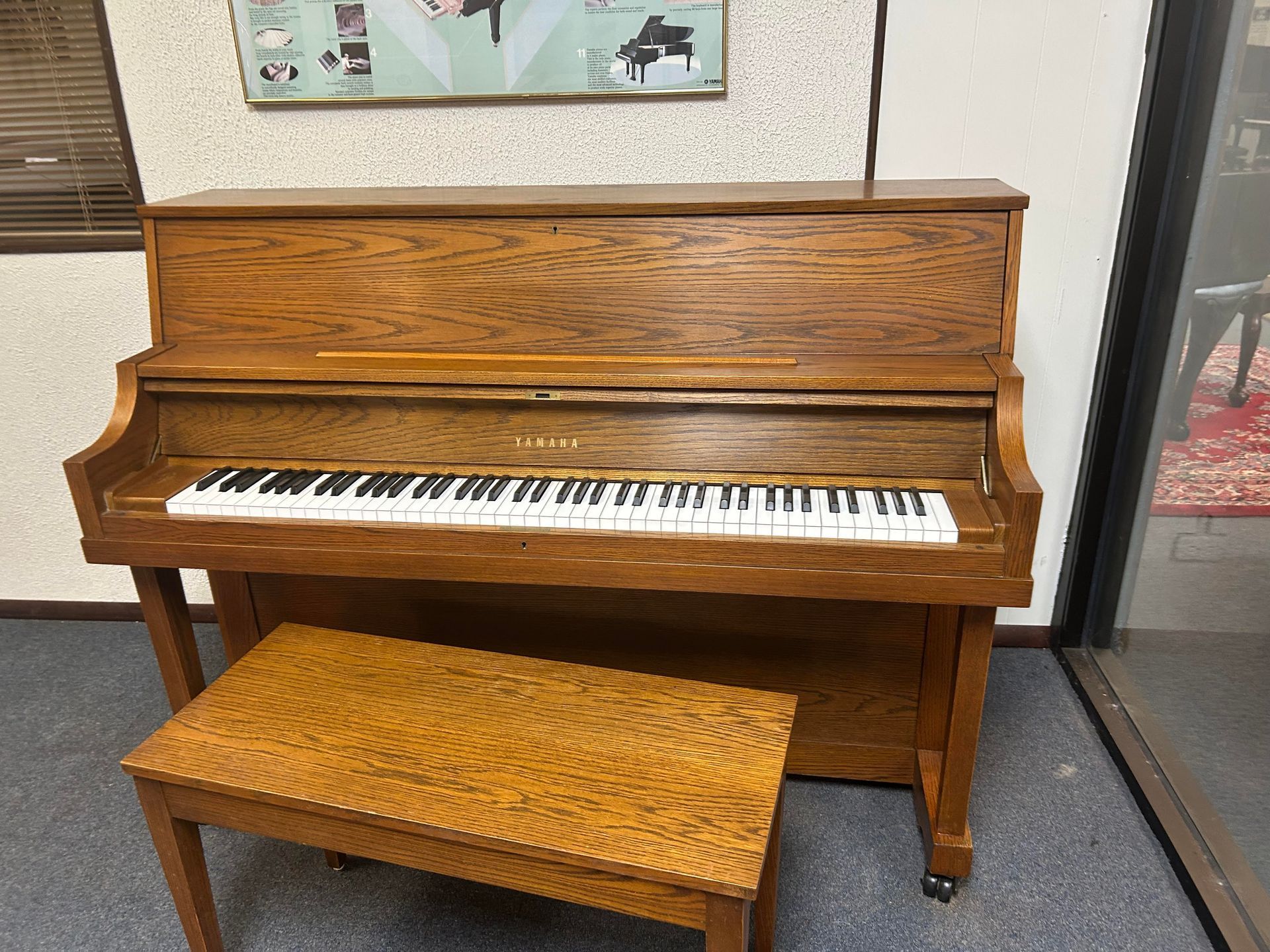 Wooden upright piano with bench in a room.