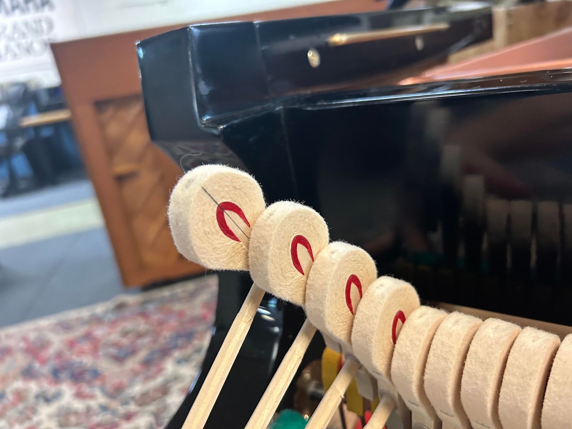 Close-up of piano hammers with felt heads and red stripes, part of the internal mechanism.