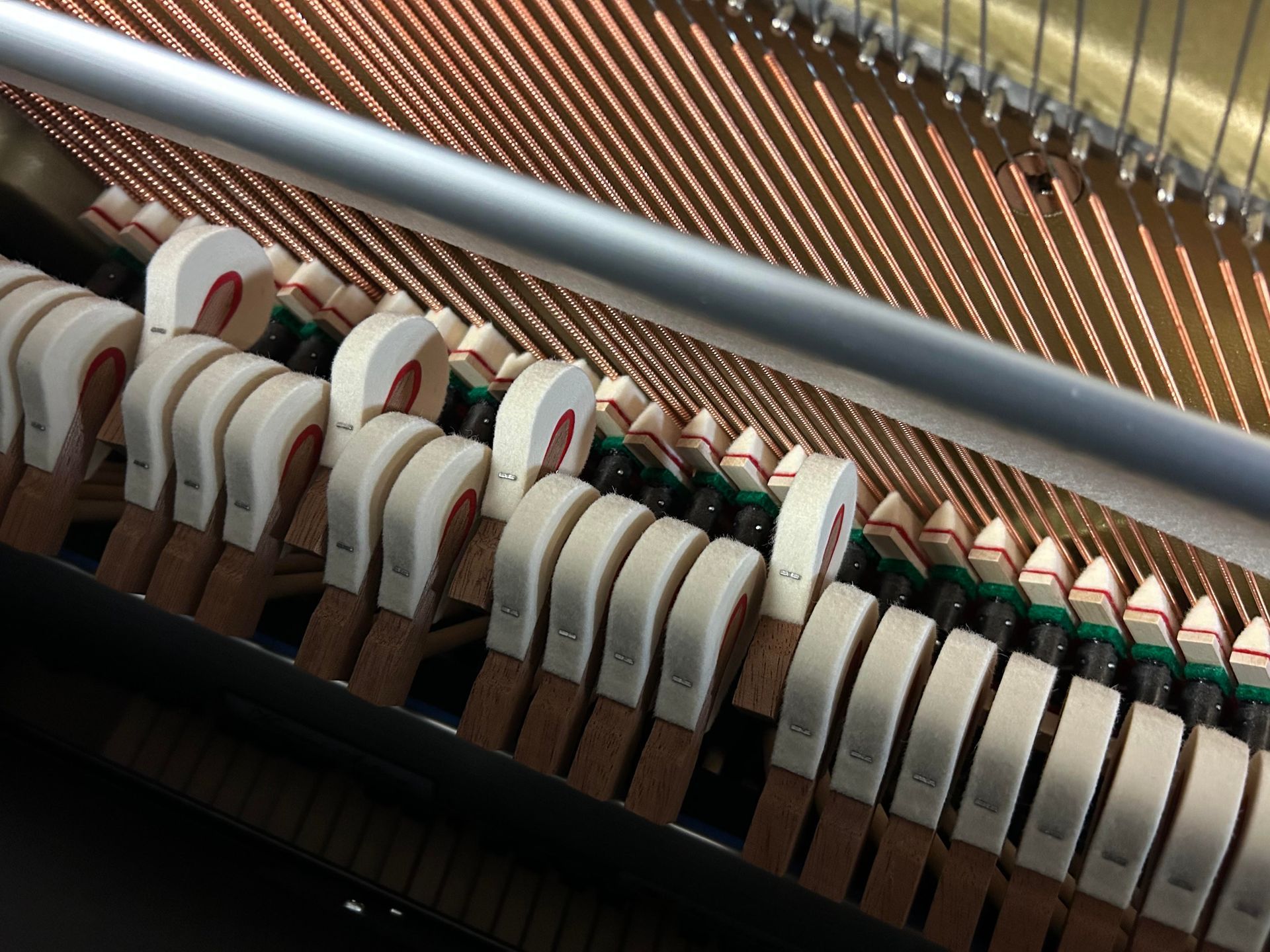 Close-up view of a piano's inner mechanics: hammers, strings, and soundboard.
