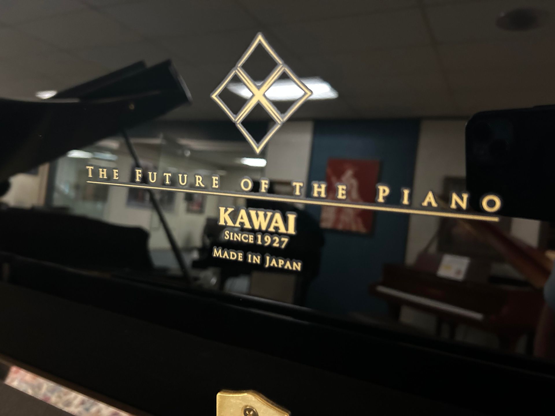 Close-up of a Kawai piano logo on a black surface, with text