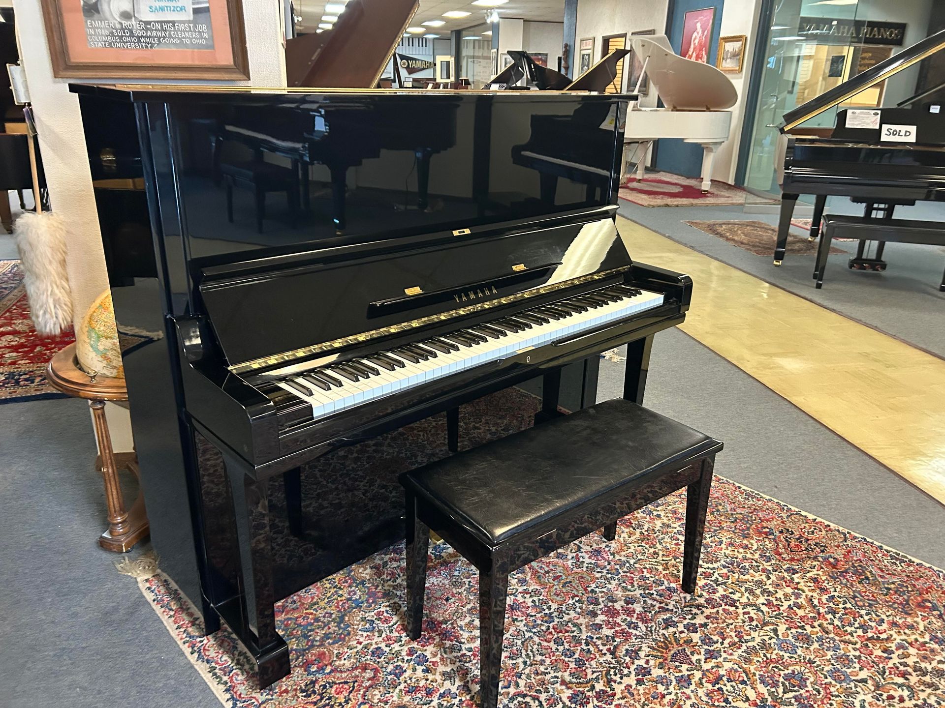 A black upright piano with a bench in a room.