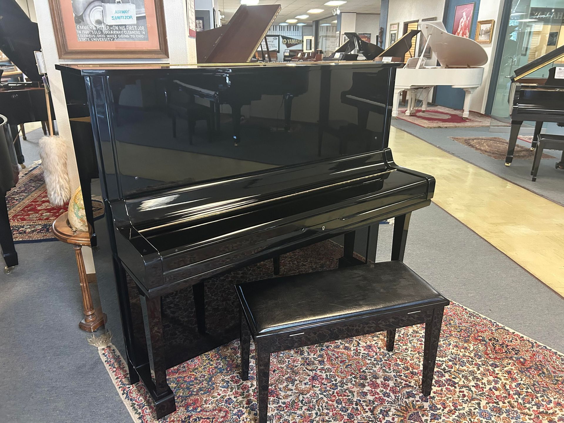A black piano is sitting on a rug in a room.